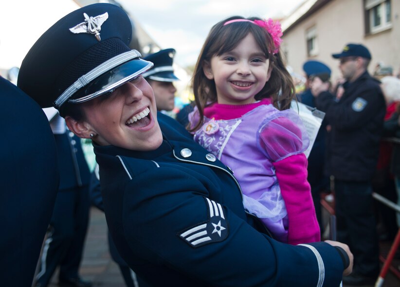 Senior AIrman Carolyn Sierichs, USAFE band member, interacts with a young crowd member during an annual Fasching parade, March 4, 2014, Ramstein Village, Germany. This annual event is a pre-Lenten carnival, which is celebrated with the donning of wild and fancy costumes to chase away the evil spirits of winter in preparation for spring. (U.S. Air Force photo/Airman 1st Class Jordan Castelan)