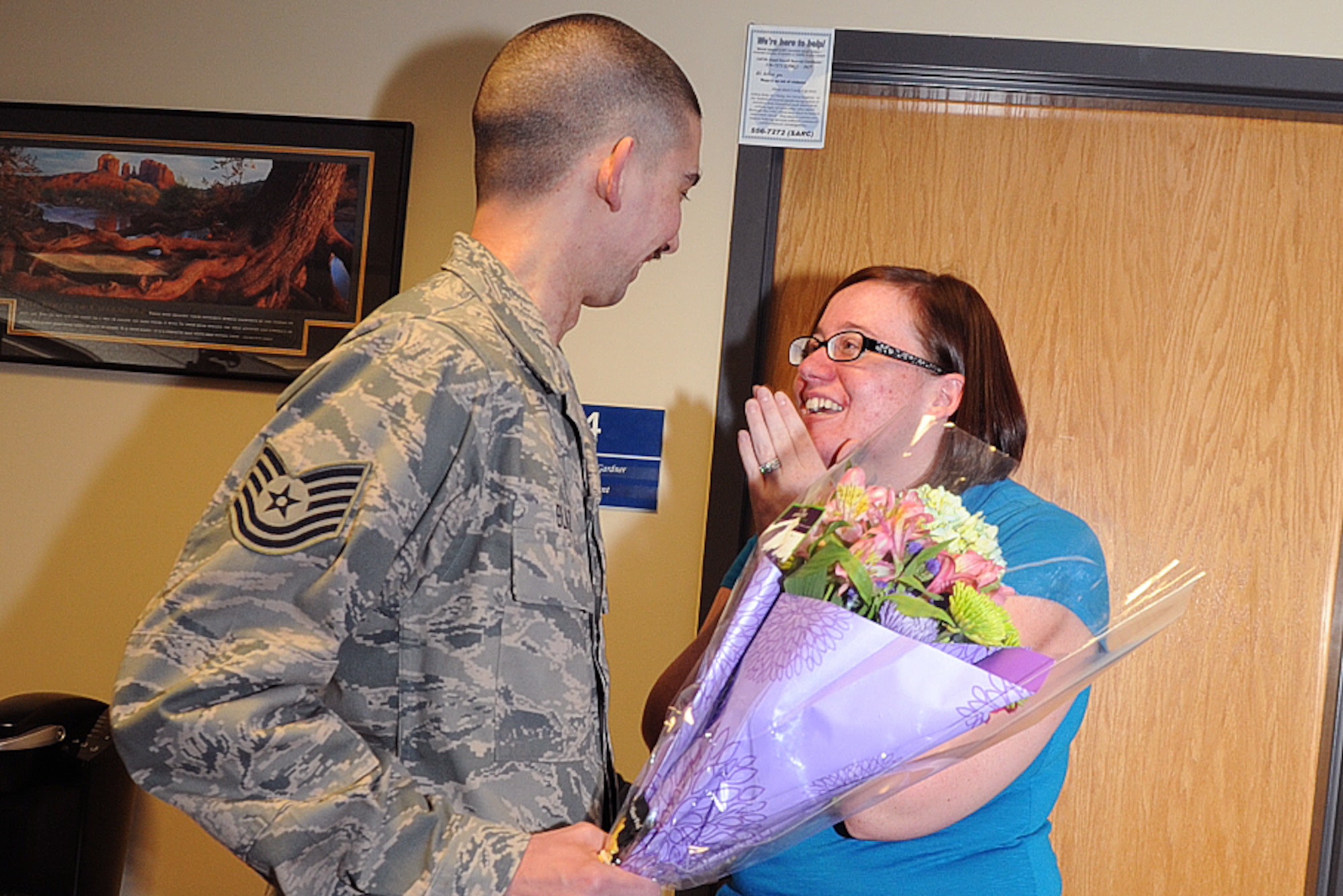 PETERSON AIR FORCE BASE, Colo. – Tech. Sgt. James Blaz, 21st Comptroller Squadron deputy disbursing officer and Government Travel Card program coordinator, surprises his wife Brandi Feb. 28 with an unannounced return from a four-month overseas deployment. Blaz had assistance from his colleagues to lure his unsuspecting wife to the 21st CPTS office where he emerged from an adjoining office with flowers and hugs for his astonished wife. Blaz spent four months at Al Udeid Air Base, Qatar, where he was the paying agent and cashier for Al Udeid and forward operating bases. (U.S. Air Force photo/Rob Bussard)