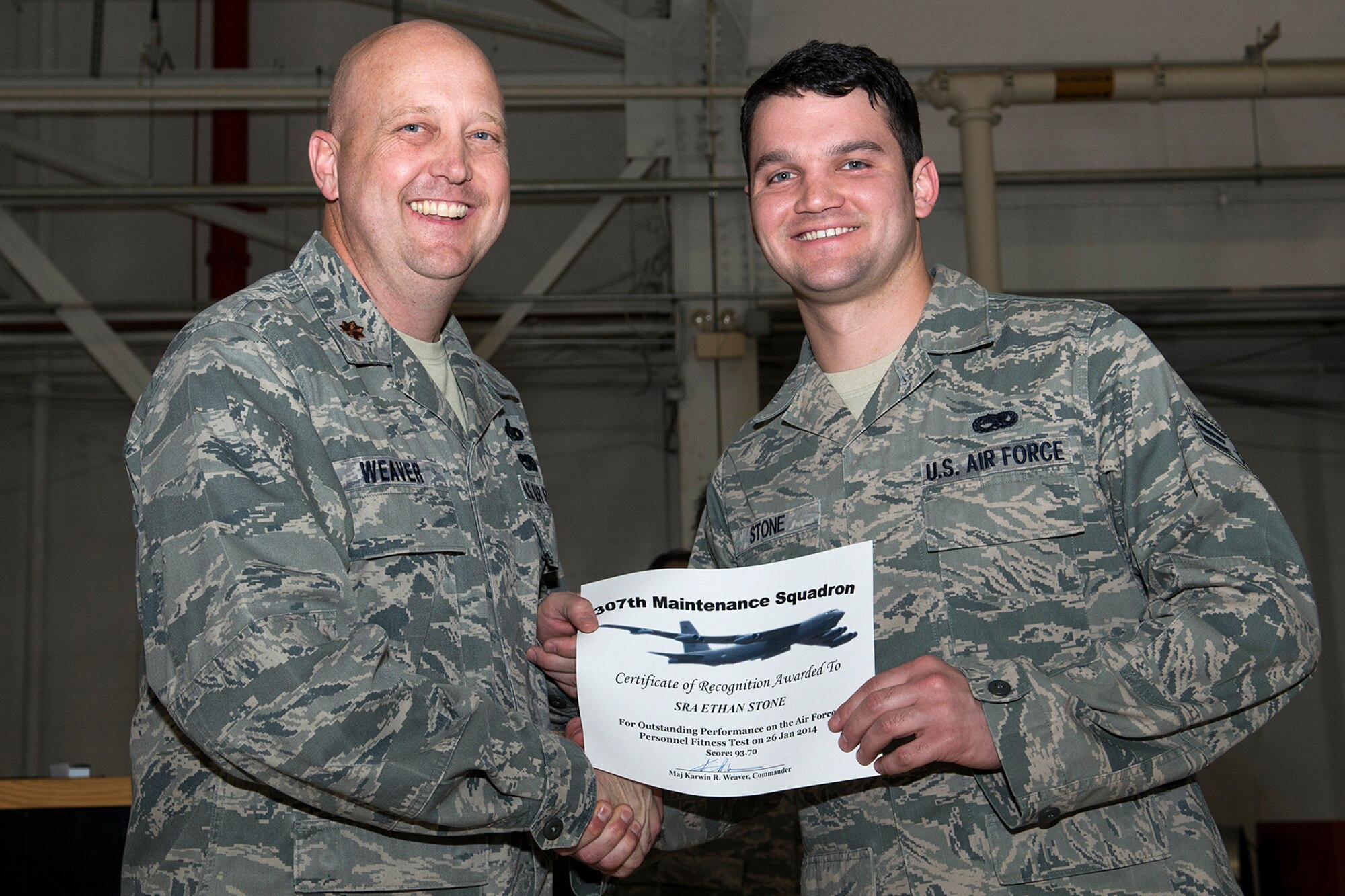 U.S. Air Force Maj. Karwin Weaver, 307th Maintenance Squadron commander, presents a Certificate of Recognition to Senior Airman Ethan Stone, Mar. 1, 2014, Barksdale Air Force Base, La. Stone received the certificate for scoring over 90 percent or over on the Air Force Personnel Fitness Test. (U.S. Air Force photo by Master Sgt. Greg Steele/Released)