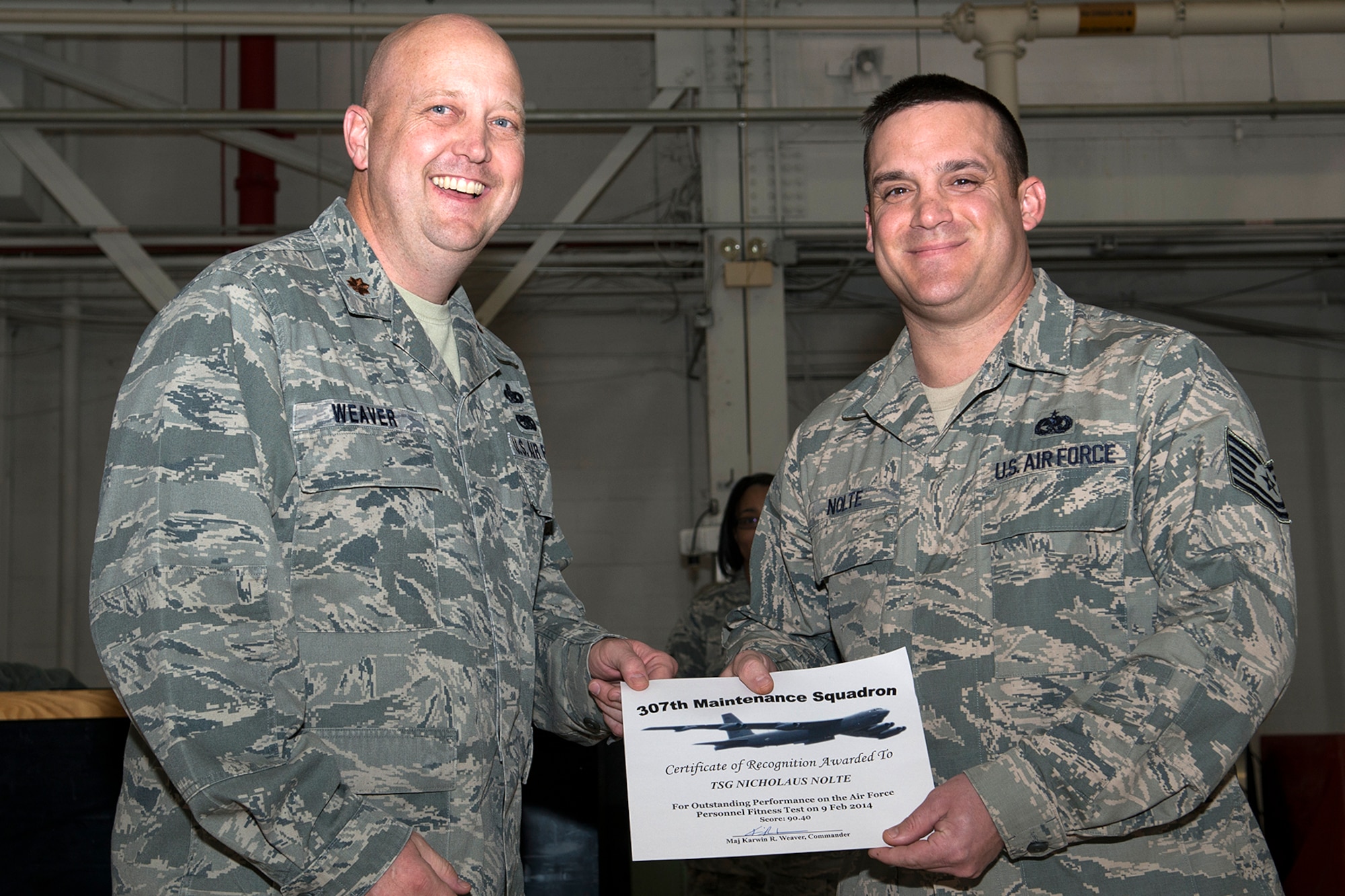 U.S. Air Force Maj. Karwin Weaver, 307th Maintenance Squadron commander, presents a Certificate of Recognition to Tech. Sgt. Nicholaus Nolte, Mar. 1, 2014, Barksdale Air Force Base, La. Nolte received the certificate for scoring over 90 percent or over on the Air Force Personnel Fitness Test. (U.S. Air Force photo by Master Sgt. Greg Steele/Released)