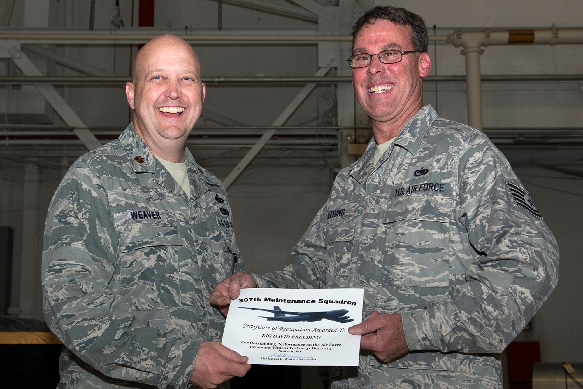 U.S. Air Force Maj. Karwin Weaver, 307th Maintenance Squadron commander, presents a Certificate of Recognition to Tech. Sgt. David Breeding, Mar. 1, 2014, Barksdale Air Force Base, La. Breeding received the certificate for scoring over 90 percent or over on the Air Force Personnel Fitness Test. (U.S. Air Force photo by Master Sgt. Greg Steele/Released)