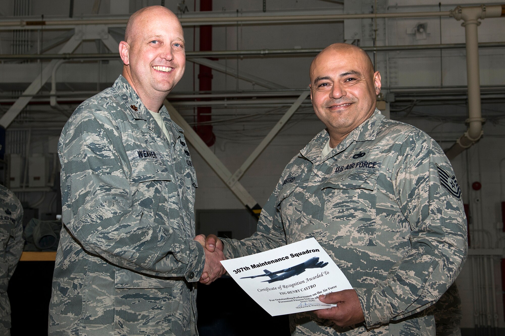 U.S. Air Force Maj. Karwin Weaver, 307th Maintenance Squadron commander, presents a Certificate of Recognition to Tech. Sgt. Henry Castro, Mar. 1, 2014, Barksdale Air Force Base, La. Castro received the certificate for scoring over 90 percent or over on the Air Force Personnel Fitness Test. (U.S. Air Force photo by Master Sgt. Greg Steele/Released)