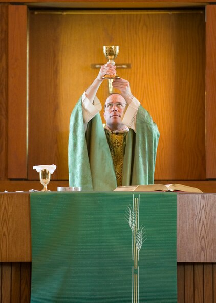 Chaplain (Capt.) Louis Mattina, 436th Airlift Wing chaplain, raises a chalice during the Eucharist portion of Sunday Catholic Mass Feb. 23, 2014, at Chapel Two on Dover Air Force Base, Del. Mattina, an Individual Mobilization Augmentee Reservist, splits his time between serving as a priest in the Diocese of Metuchen, N.J. and a chaplain at Dover AFB. (U.S. Air Force photo/Airman 1st Class Zachary Cacicia)