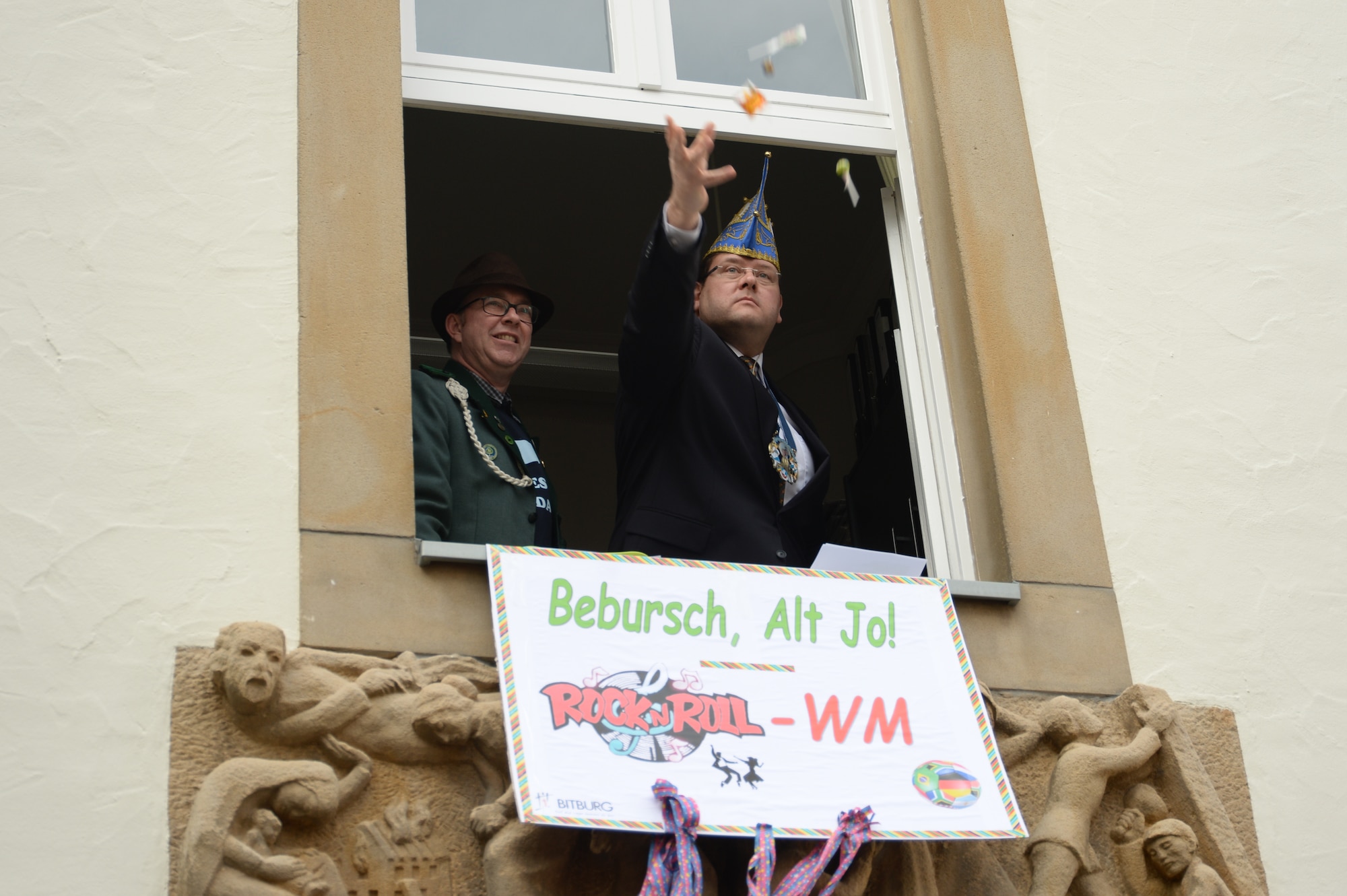 Joachim Kandels, mayor of Bitburg  throws candy to revelers on the street corner below during a Fasching celebration at his city hall in Bitburg, Germany, Feb. 27, 2014. Kandels oversaw the Fasching tradition of the storming of the city hall by female citizens. (U.S. Air Force photo by Staff Sgt. Joe W. McFadden/Released)