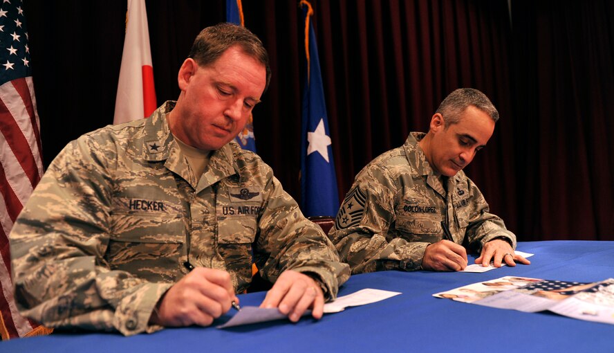 U.S. Air Force Brig. Gen. James Hecker, 18th Wing commander, and Chief Master Sgt. Ramon Colon-Lopez, 18th Wing command chief, fill out their Air Force Assistance Fund forms at the Kadena Officer's Club on Kadena Air Base, Japan, March 3, 2014.The AFAF campaign provides assistance for the Air Force's active-duty, retirees, reservists, guard members and their dependents, including surviving spouses in need. (U.S. Air Force photo by Naoto Anazawa)