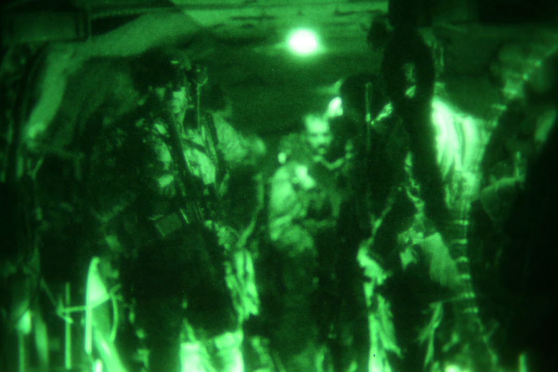 As seen through a night-vision device, Afghan commandos and U.S. Special Forces soldiers prepare to exit a CH-47 Chinook helicopter to begin a clearing operation in Darazkol village in Afghanistan's Kandahar province, Feb. 23, 2014.