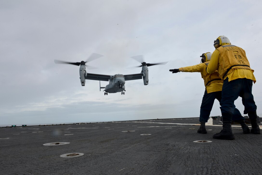 Boatswain's Mate 3rd Class directs a MV-22 Osprey as it conducts carrier qualification aboard the amphibious dock landing ship USS Gunston Hall (LSD-44). The carrier qualification gave the pilots from Special-Purpose Marine Air-Ground Task Force Crisis Response and Spanish Maneuver Helicopter Battalion #4 a dedicated opportunity to practice fundamental skills associated with operating carrier-based aircraft and demonstrate acceptable levels of proficiency.