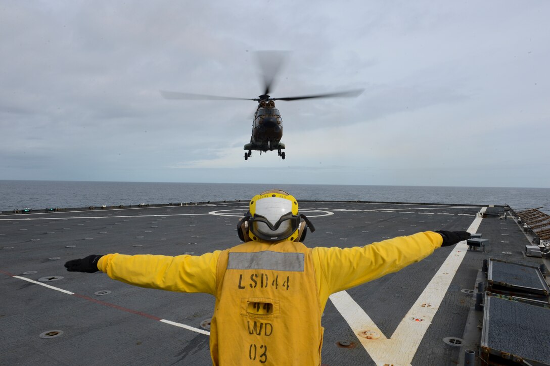 Boatswain's Mate 3rd Class Justus Dondaldson signals an AS-532 Cougar, from the Spanish Army, as it conducts carrier qualification aboard the amphibious dock landing ship USS Gunston Hall (LSD-44). The carrier qualification gave the pilots from Special-Purpose Marine Air-Ground Task Force Crisis Response and Spanish Maneuver Helicopter Battalion #4 a dedicated opportunity to practice fundamental skills associated with operating carrier-based aircraft and demonstrate acceptable levels of proficiency.
