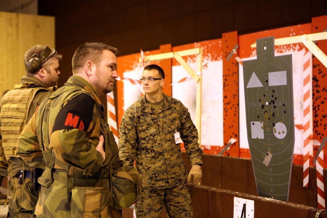 Lance Cpl. Tyler Riggs (center), a military policeman with 2nd Supply Battalion, Combat Logistics Group 25, 2nd Marine Logistics Group, and Norwegian MPs with Home Guard District 12 review their shots in an indoor firing range at Vaernes Garrison, Norway, Feb. 21, 2014. The MPs trained together to build camaraderie and operational unity prior to Cold Response 2014. Cold Response 2014 is a Norwegian-led multinational exercise above the Arctic Circle designed prepare for crisis response operations.
