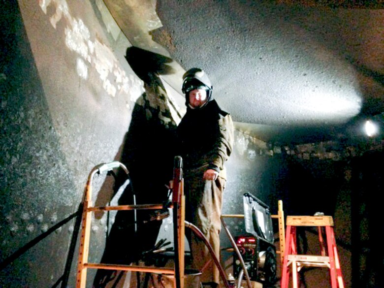 Mike Schnetzer in his supplied-air welding hood. Repairs are not unlike the process to repair a cavity in a tooth. The porous material is cut and removed by a blast of air through a process called air carbon arcing. A stainless steel filler that is harder and corrosion resistant is welded into place and then ground to create a smooth surface repairing the cavitated area. 