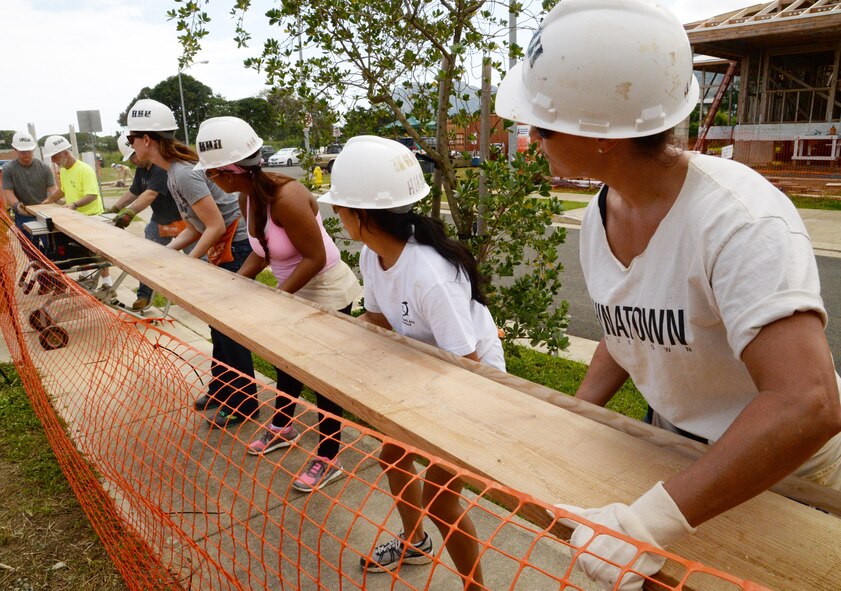 Hickam Airmen and local volunteers assist with sawing a large piece of wood during a Honolulu Habitat for Humanity volunteer day in Waimanalo, Hawaii, March 5, 2014. The Airmen, mostly part of the 15th Maintenance Group and 65th Airlift Squadron, took the day to give back to the community and help build homes for families in need. (U.S. Air Force photo/Staff Sgt. Alexander Martinez)