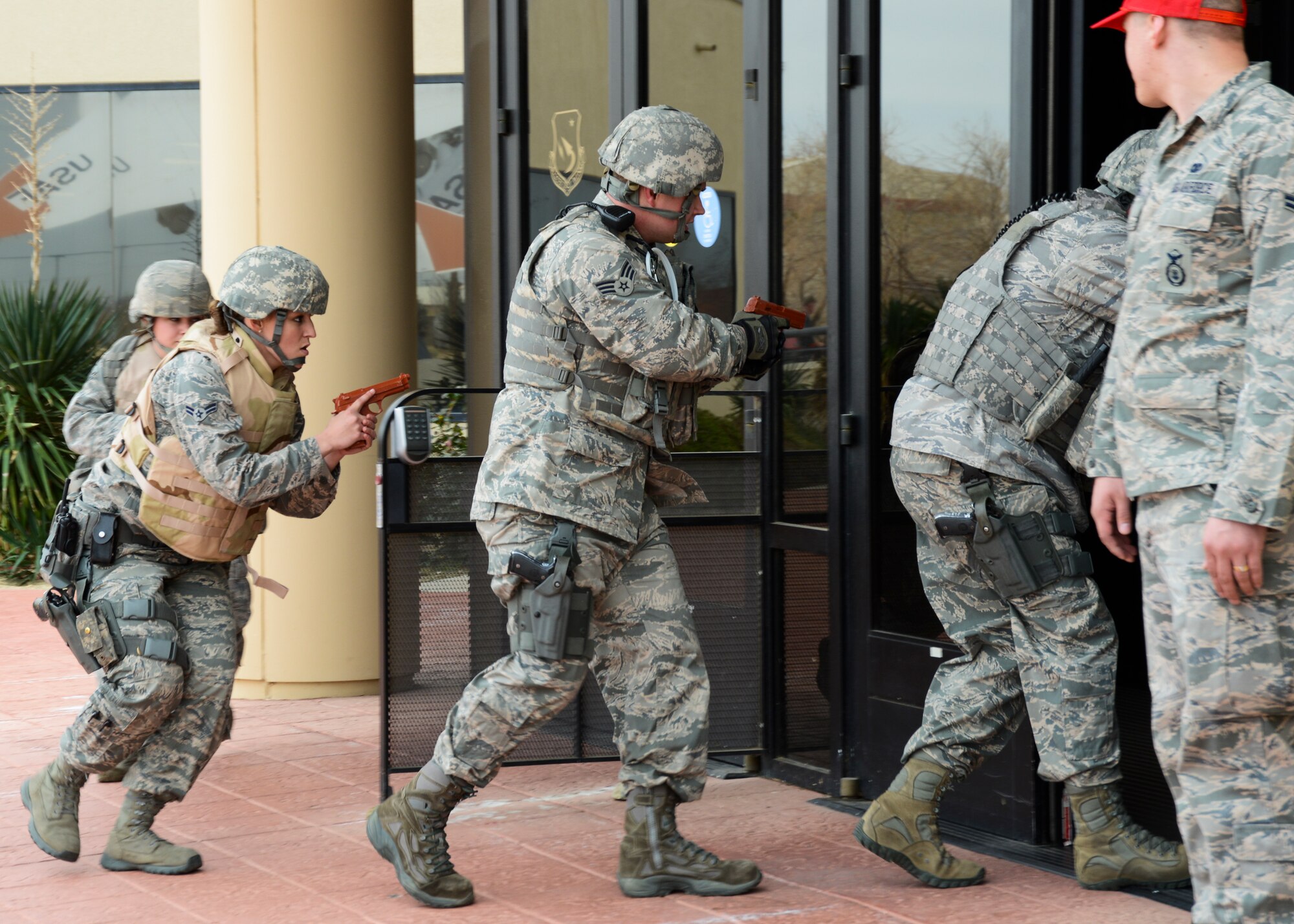 412th Security Forces Squadron defenders enter 412th Test Wing headquarters simulating an active shooter scenario. The Airmen effectively neutralized the shooter and secured the facility. To ensure safety during the exercise, the Airmen traded their real firearms for training weapons. Edwards AFB routinely conducts emergency exercises to prepare the base for possible threats, natural disasters and accidents. (U.S. Air Force photo by Rebecca Amber)