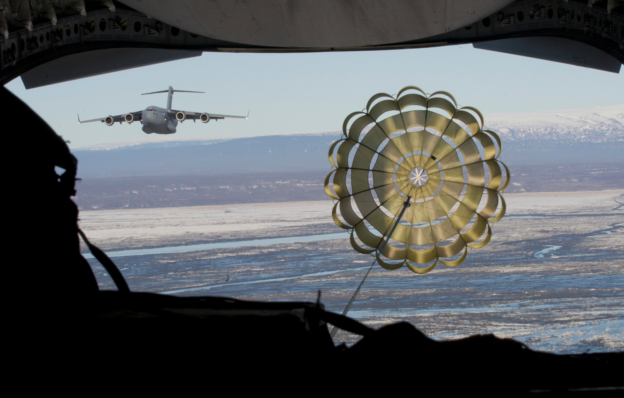 A C-17 Globemaster III from the 517th Airlift Squadron prepares to drop heavy equipment while another Globemaster III from the 535th Airlift Squadron, Joint Base Pearl Harbor-Hickam, Hawaii, flies beside the aircraft over Malemute Drop Zone, Feb. 27, 2014. (U.S. Air Force photo/Staff Sgt. Sheila deVera)
