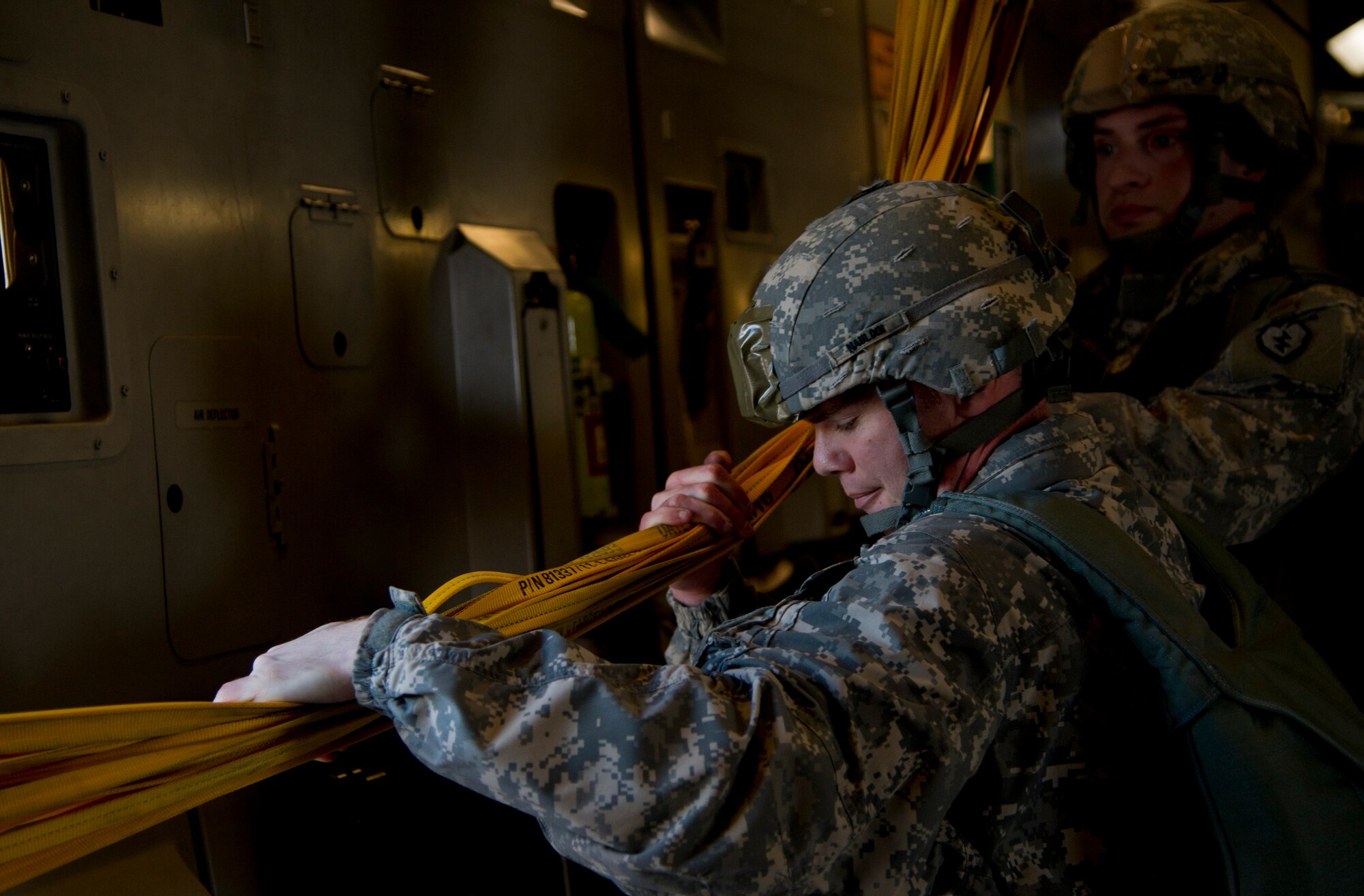 Army Capt. Michael Mauldin (foreground) and Sgt. Clayton Word pull static lines back into the aircraft over Malemute Drop Zone at Joint Base Elmendorf-Richardson, Alaska. The static line is a cord attached at one end to the aircraft and at the other to the Soldier’s parachute container, and that extracts the T-11 parachute. (U.S. Air Force photo/Staff Sgt. Sheila deVera)