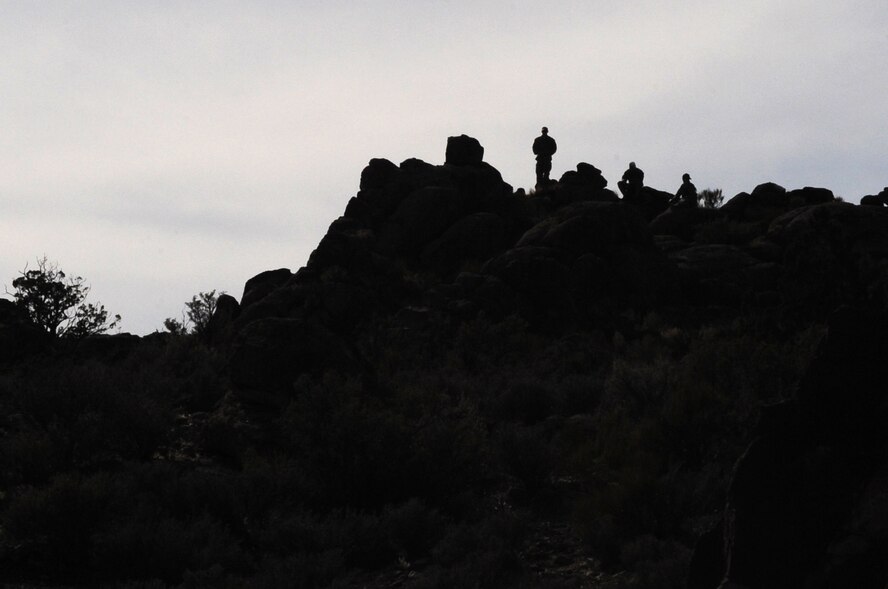 “Enemy forces,” played by U.S. Air Force survival, evasion, resistance and escape specialists, scan the mountainside from atop a range peak March 4, 2014, in Southern Nevada. As part of Red Flag 14-2, SERE specialists used their training to search for a downed pilot in the desolate countryside surrounding Nellis Air Force Base, Nev.  (Air Force photo/Staff Sgt. Chuck Broadway)