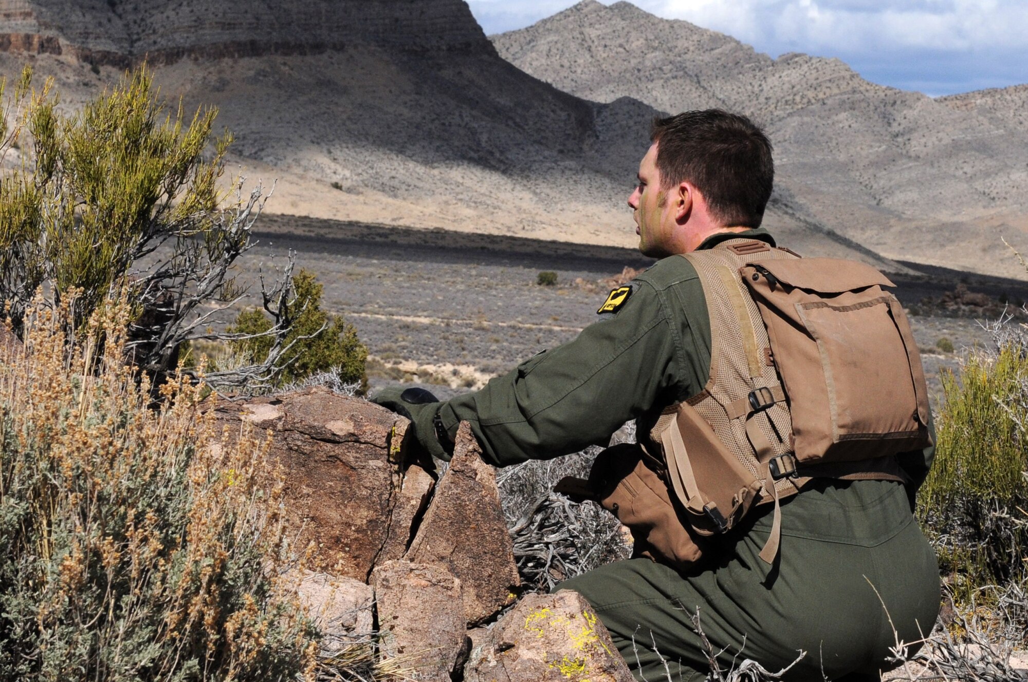 U.S. Air Force 1st Lt. Ryan Gipson, 336th Fighter Squadron F-15E Strike Eagle pilot, scans for “enemy forces” on a barren Nevada range March 4, 2014, during Red Flag 14-2. Armed with basic survival equipment, Gipson portrayed a downed pilot forced to use his survival, evasion, resistance and escape skills to elude capture. (Air Force photo/Staff Sgt. Chuck Broadway)