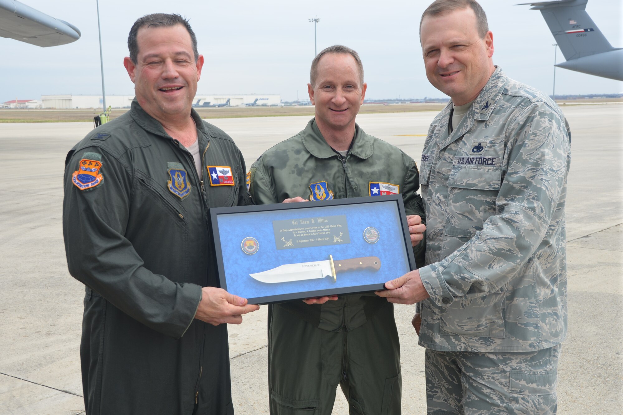 (Left) Lt. Col. John Martino, 733rd Training Squadron commander and (right) Col. Craig Petersen, 433rd Mission Support Group commander present Col. Adam Willis, 433rd Operations Group commander with a memento from the 433rd Airlift Wing after his final flight as OG commander. Willis leaves the “Alamo Wing” for the 908th Airlift Wing, Maxwell AFB, Ala. (U.S. Air Force photo by Senior Master Sgt. Minnie Jones /Released)