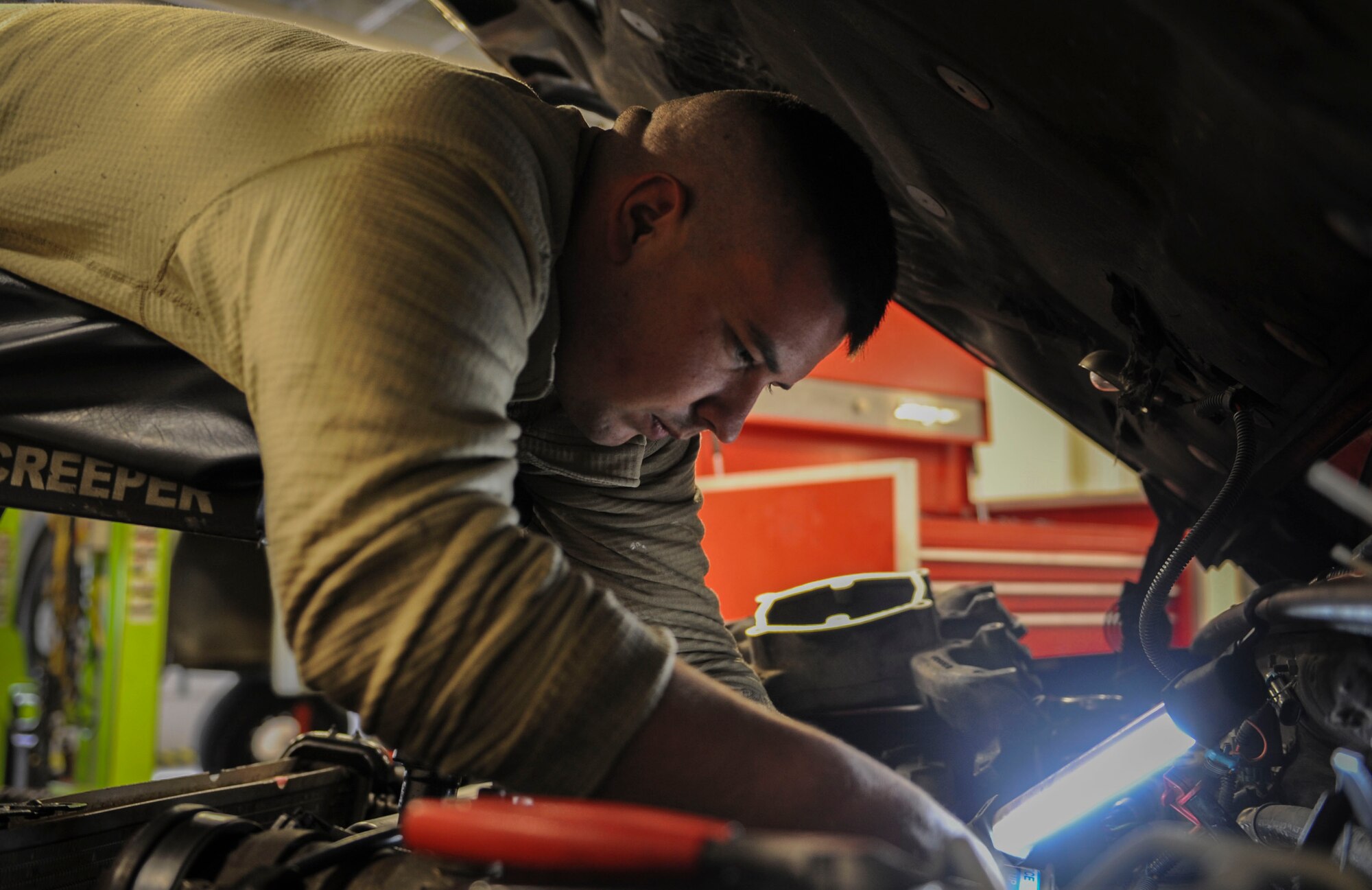 U. S. Air Force Senior Airman Josh Flodder, 23d Logistics Readiness Squadron vehicle vehicular equipment maintenance journeyman, works on a truck engine at Moody Air Force Base, Ga., March 5, 2014. Flodder used a topside creeper allowing him to reach the part he needed to fix. (U.S. Air Force photo by Airman 1st Class Alexis Millican/Released)