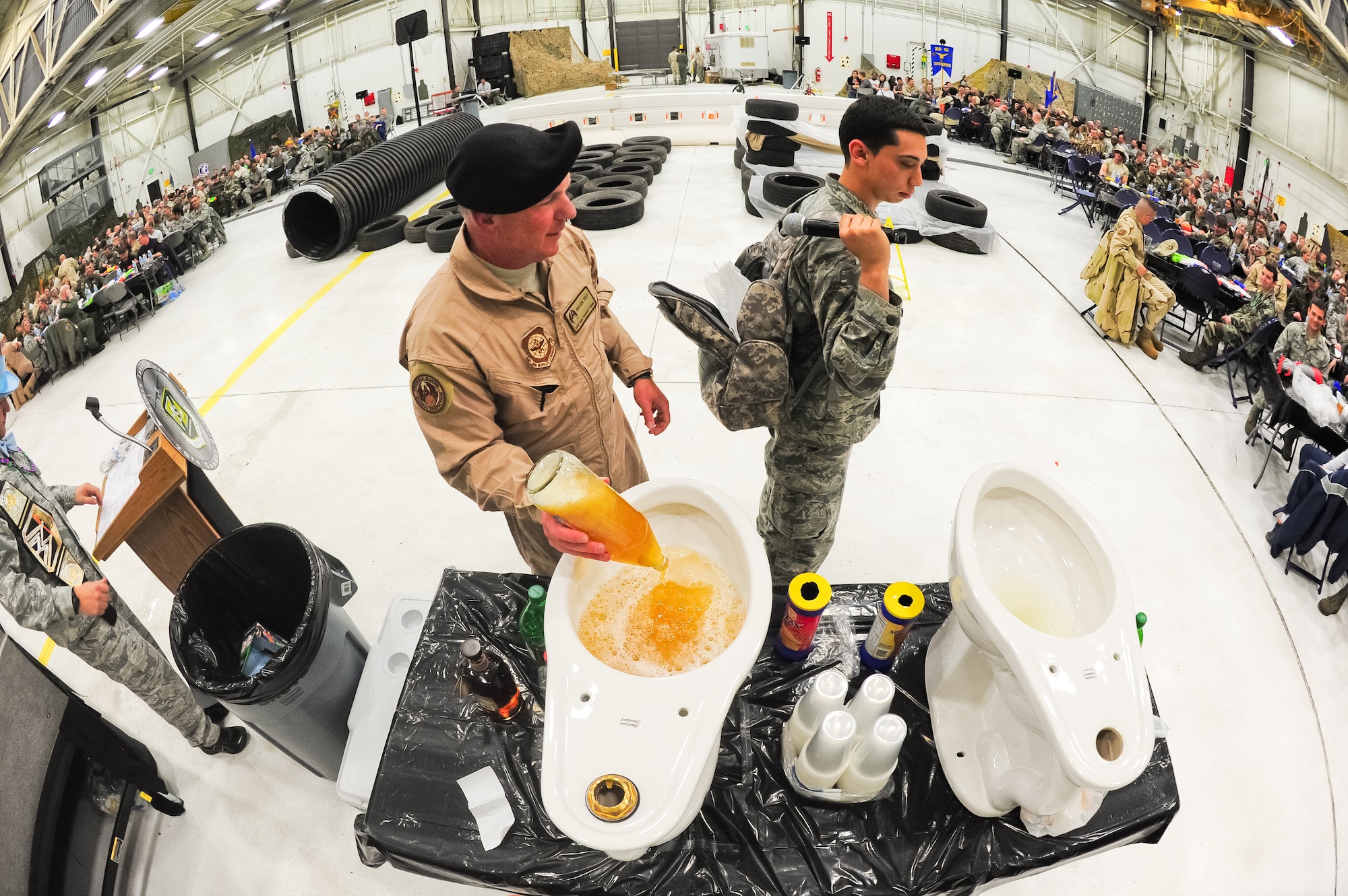 Air Force Reserve Chief Master Sgt. Gary Brown reveals his special beverage going into the “grog bowl” with the help of Airman Roberto Simental March 1, 2014, during the 310th Space Wing's Combat Dining In/Annual Awards Ceremony at Peterson Air Force Base, Colo. The wing sponsored the event to both recognize its annual award winners and bring together the Reservists to enjoy an evening of esprit de corps, unit morale and camaraderie. Brown is the wing’s command chief master sergeant, while Simental was chosen because he is the lowest ranking and youngest Airman in the 310th SW. (U.S. Air Force photo/Tech. Sgt. Nicholas B. Ontiveros)