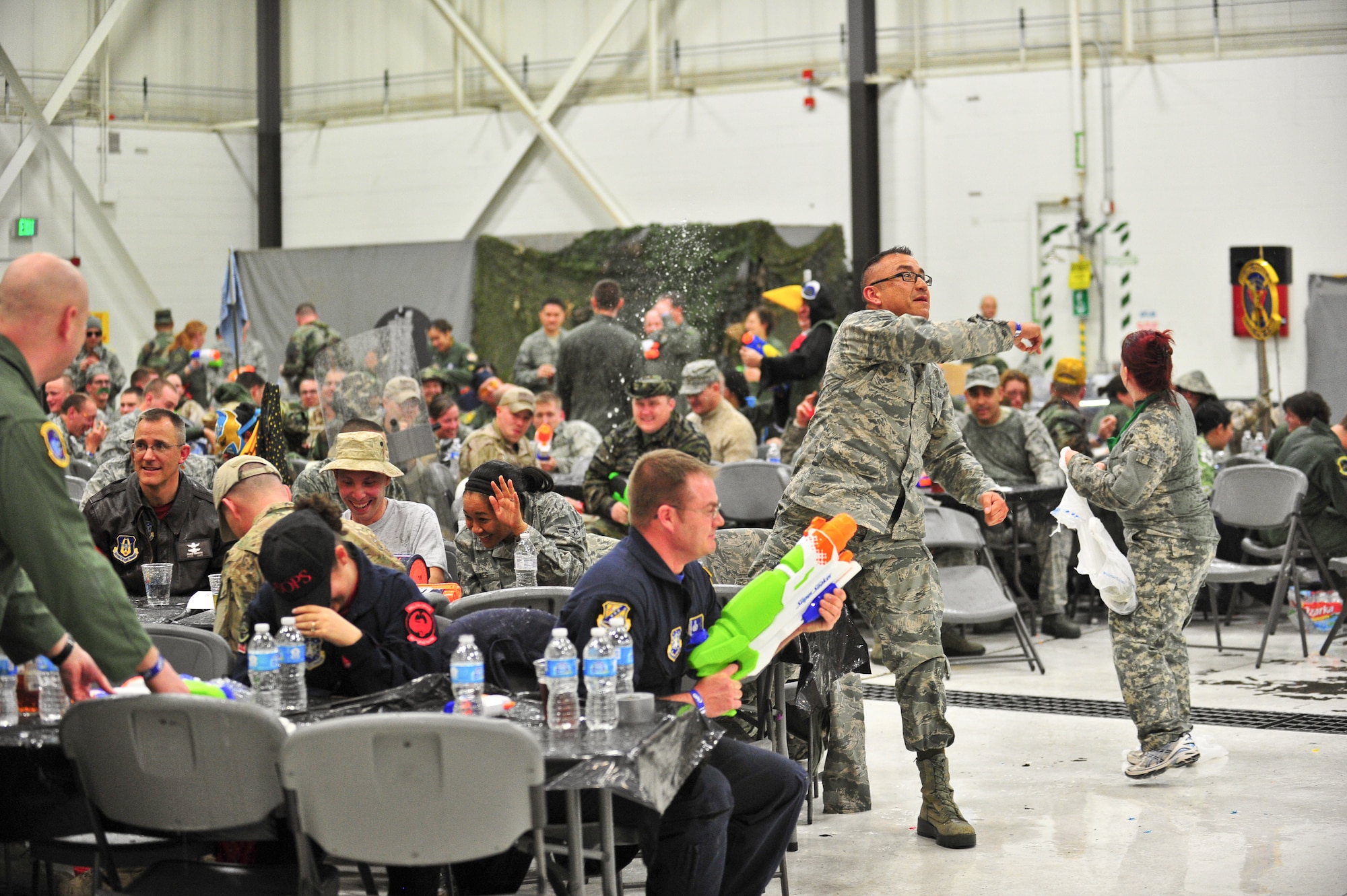 Air Force Reservists take cover and return fire as an impromptu water fight begins March 1, 2014, during the 310th Space Wing's Combat Dining In/Annual Awards Ceremony at Peterson Air Force Base, Colo. The wing sponsored the event to both recognize its annual award winners and bring together the Reservists to enjoy an evening of esprit de corps, unit morale and camaraderie. (U.S. Air Force photo/Tech. Sgt. Nicholas B. Ontiveros)