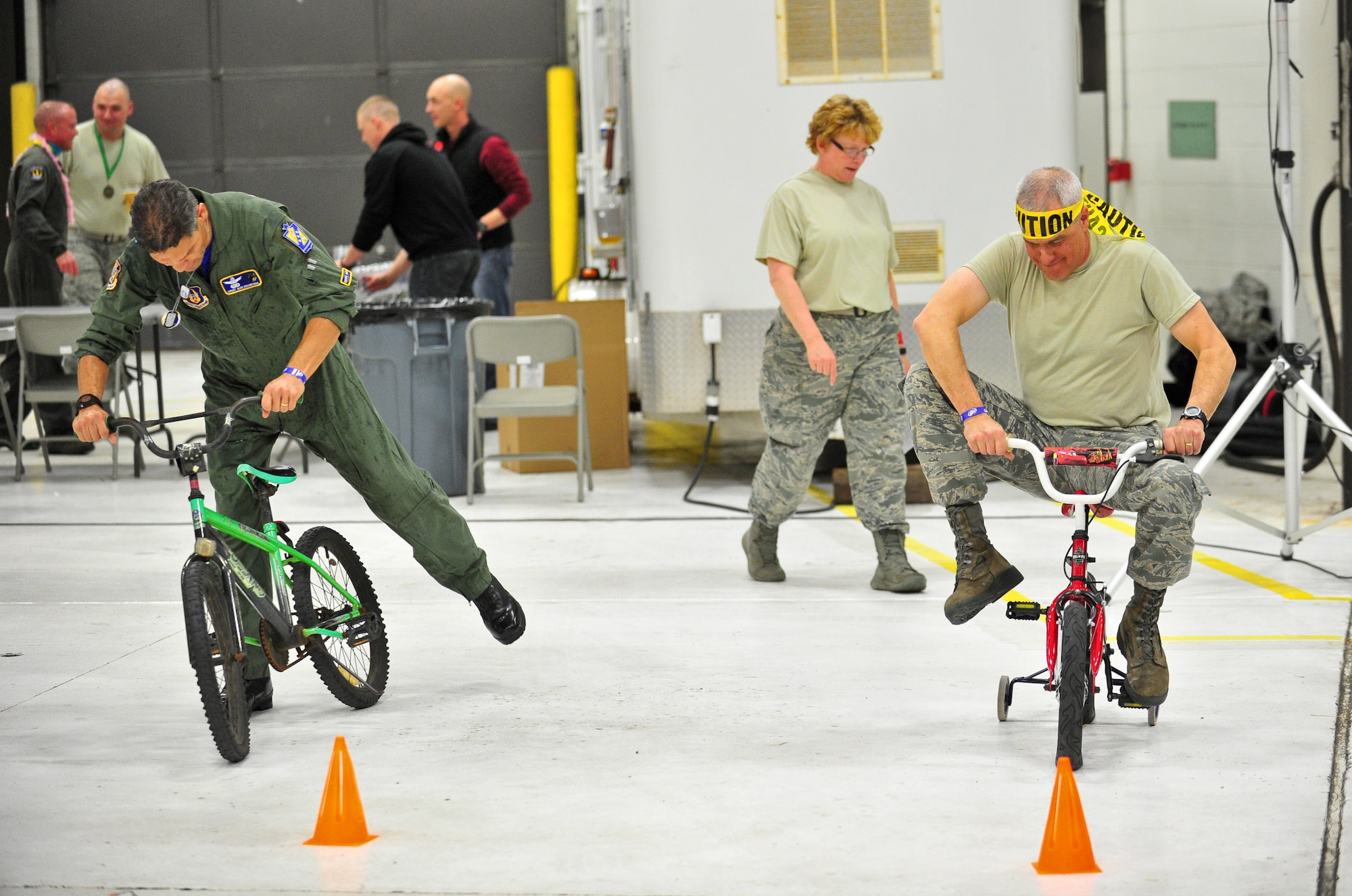 Air Force Reservists Chief Master Sgt. Alex Escarcega (left) and Lt. Col. Rives Duncan try to ride children’s bikes at the start of an obstacle course March 1, 2014, during the 310th Space Wing's Combat Dining In/Annual Awards Ceremony at Peterson Air Force Base, Colo. The wing sponsored the event to both recognize its annual award winners and bring together the Reservists to enjoy an evening of esprit de corps, unit morale and camaraderie. Escarcega is the 310th Operations Group chief enlisted manager and Duncan is the wing  chaplain. (U.S. Air Force photo/Tech. Sgt. Nicholas B. Ontiveros)