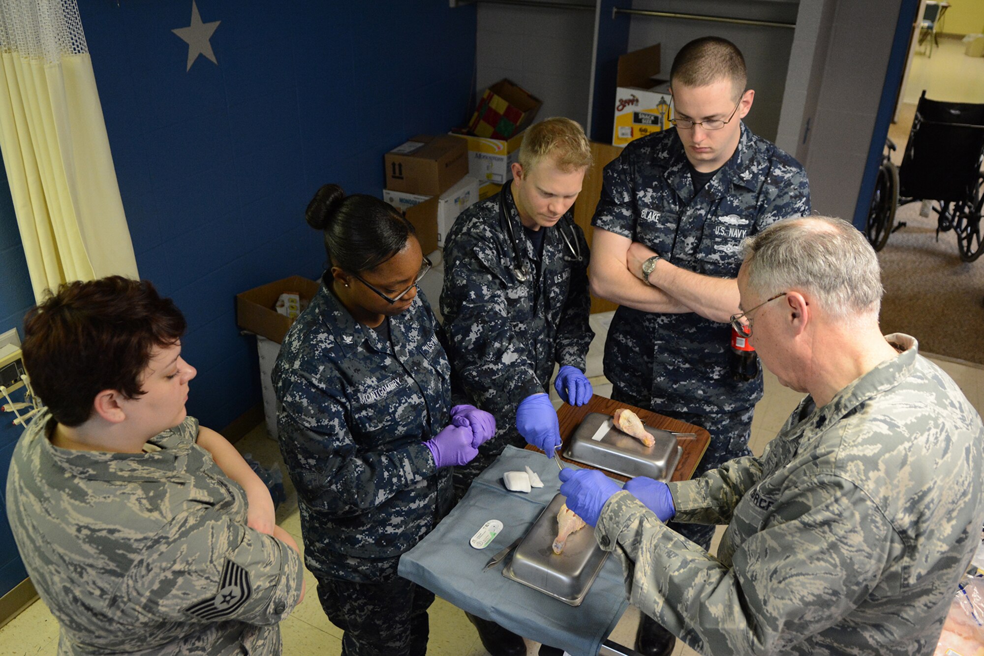 Navy and Air National Guard personnel use a chicken leg to practice putting sutures in a cut during Cajun Care 2014 in Abbeville, La., March 2, 2014. The different services used the 10-day mission to train together, and provide health, dental and optometry services to local residents of Abbeville, La., and the surrounding areas. (Air National Guard photo by Senior Airman Andrea F. Liechti)