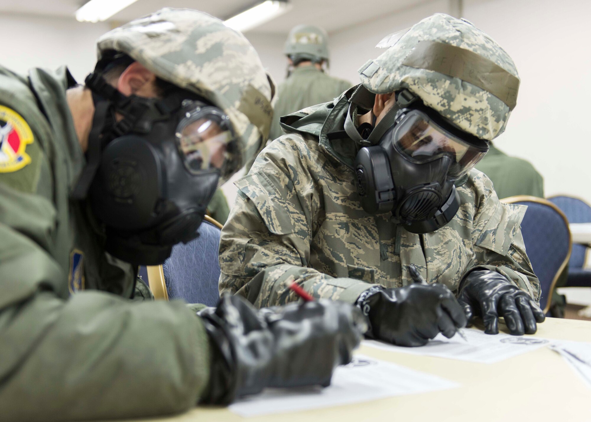 Two Airmen complete a checklist while wearing their mission-oriented protective posture gear at Yokota Air Base, Japan, March 5, 2014.  Yokota is continuing their week-long Samurai Readiness Inspection, where they are being tested to perform under the challenging scenarios such as a chemical warfare attack.  (U.S. Air Force photo by Airman 1st Class David Danford / released)