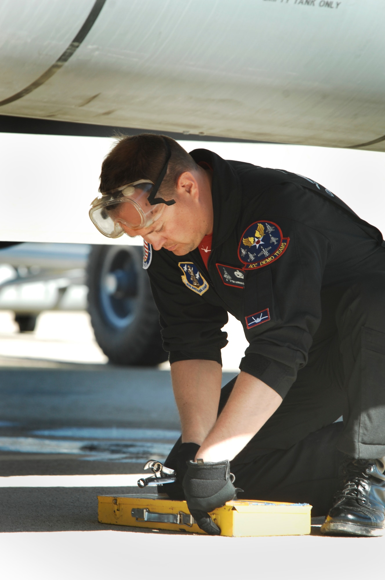 U.S. Air Force Tech. Sgt. Harrison Southworth, Air Combat Command F-22 Raptor Demonstration Team crew chief, grabs tools to change an F-22 Raptor tire on the flightline at Davis-Monthan Air Force Base, Ariz. March 2, 2014. The ACC Demonstration team worked with Holloman AFB to overnight replacement tires and to send a maintenance crew to assist with the change. (U.S. Air Force photo by Staff Sgt. Angela Ruiz/Released)