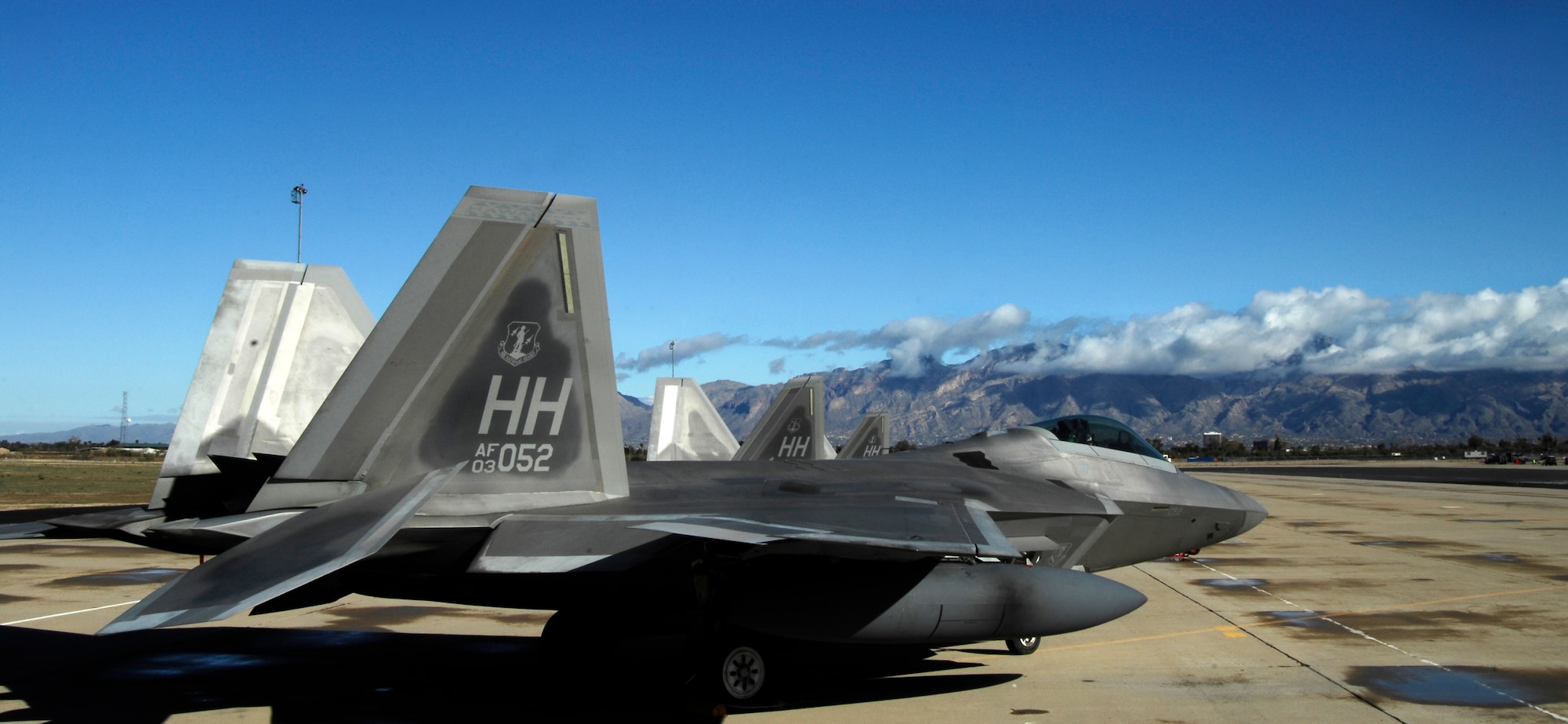 Three F-22 Raptors from Hickam Air Force Base, Hawaii, are parked on the flightline at Davis-Monthan Air Force Base., Ariz., March 2, 2014. Four F-22’s were diverted to D-M and during landing three of the Raptors’ right side tires deflated as a safety precaution due to an increase in tire pressure, caused by the weather conditions and landing friction. (U.S. Air Force photo by Staff Sgt. Angela Ruiz/Released) 