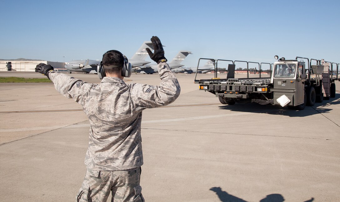 TRAVIS AIR FORCE BASE, Calif. -- Senior Airman Spencer A. Moon, an air transportation specialist with the 82nd Aerial Port Squadron, marshals a Tunner 60K aircraft cargo loader at Travis Air Force Base, Calif., Feb. 23, 2014. During the Unit Training Assembly of Feb. 22-23, squadrons from across the 349th Air Mobility Wing conducted interrelated exercise scenarios, providing Reservists opportunities to achieve core skill proficiency training.   On this particular C-17 Globemaster III aeromedical evacuation sortie, key training events were achieved for members from the 349th Operations, Maintenance, Support and Medical Groups. (U.S. Air Force photo / Lt. Col. Robert Couse-Baker)