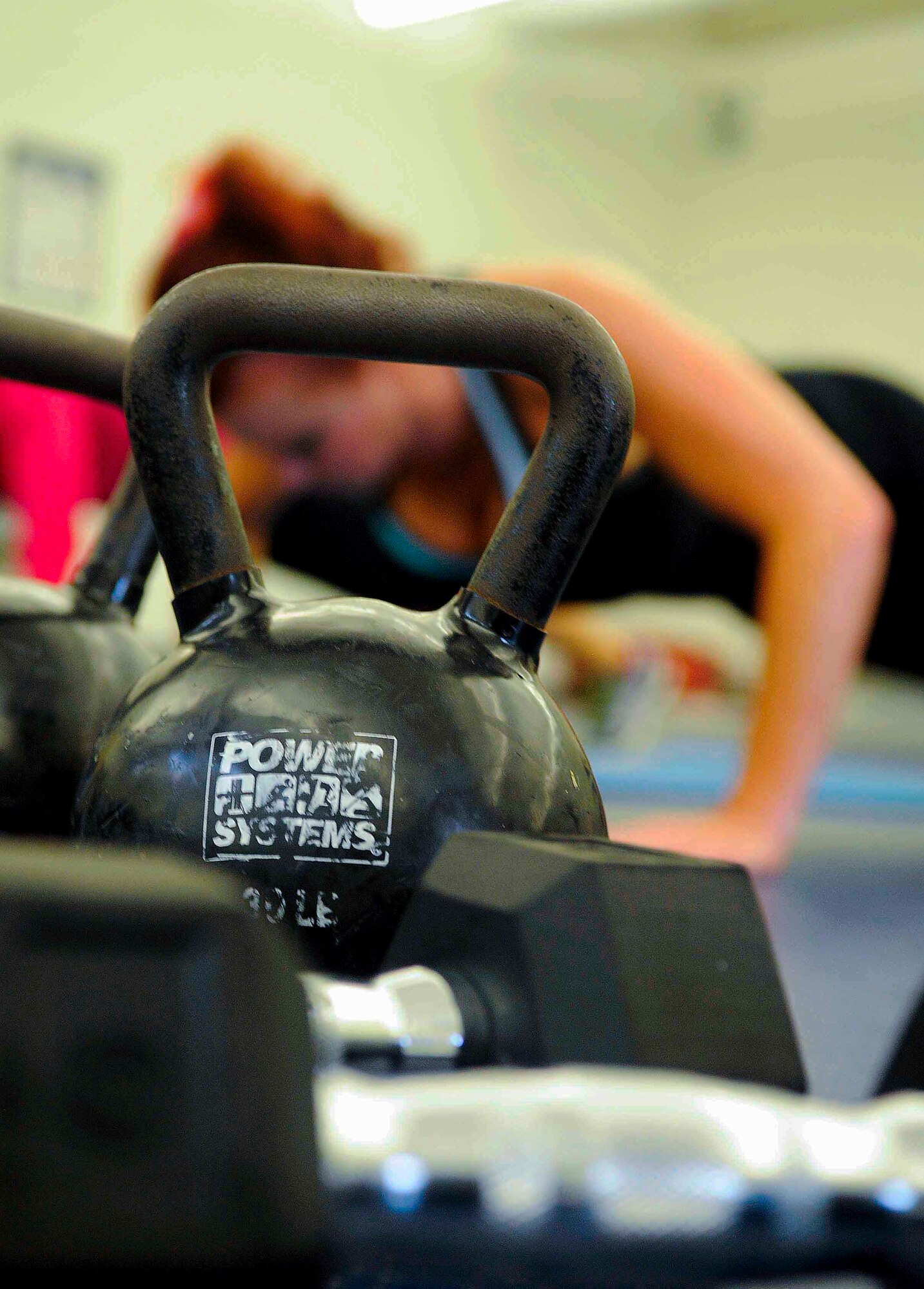 Lisa Pizzo, lead group fitness instructor, does push-ups at the Aderholt Gym on Hurlburt Field, Fla., March 3, 2014. Participants kept weights in easy reach because they were used throughout the workout. (U.S. Air Force photo/Airman 1st Class Andrea Posey)