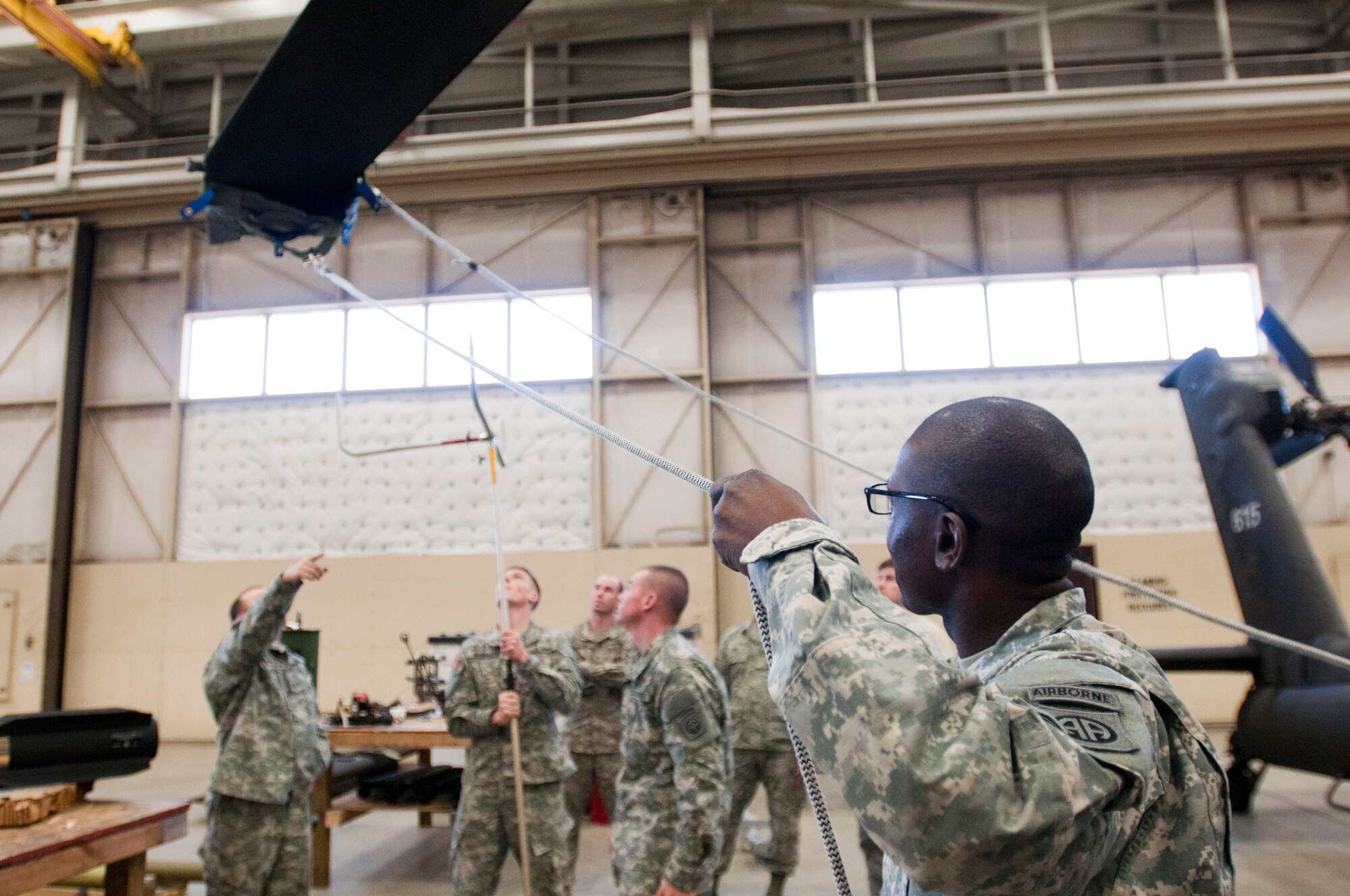 Pfc. Fanuel Chageza, foreground, tightens the cable on a Unit Maintenance Aerial Recovery Kit blade sleeve to stabilize the rotary blades of an AH-64 Apache Helicopter during training at Simmons Army Airfield, Feb. 24. 82nd Combat Aviation Brigade troops hosted joint Downed Aircraft Recovery Team and Crash Damaged Disabled Aircraft Recovery training with Airmen from Pope Army Airfield at Simmons Army Airfield. Soldiers from 122nd Aviation Support Battalion and 1-82 Attack Reconnaissance Battalion, and Airmen from 440th Maintenance Group and 2nd Airlift Squadron, 43rd Airlift Group, practiced using the Unit Maintenance Aerial Recovery Kit on an AH-64 Apache helicopter. DART and CDDAR teams are responsible for recovering aircraft after they crash or become disabled and can no longer fly. (Photo by U.S. Army Staff Sgt. April Campbell, 82nd Combat Aviation Brigade Public Affairs)