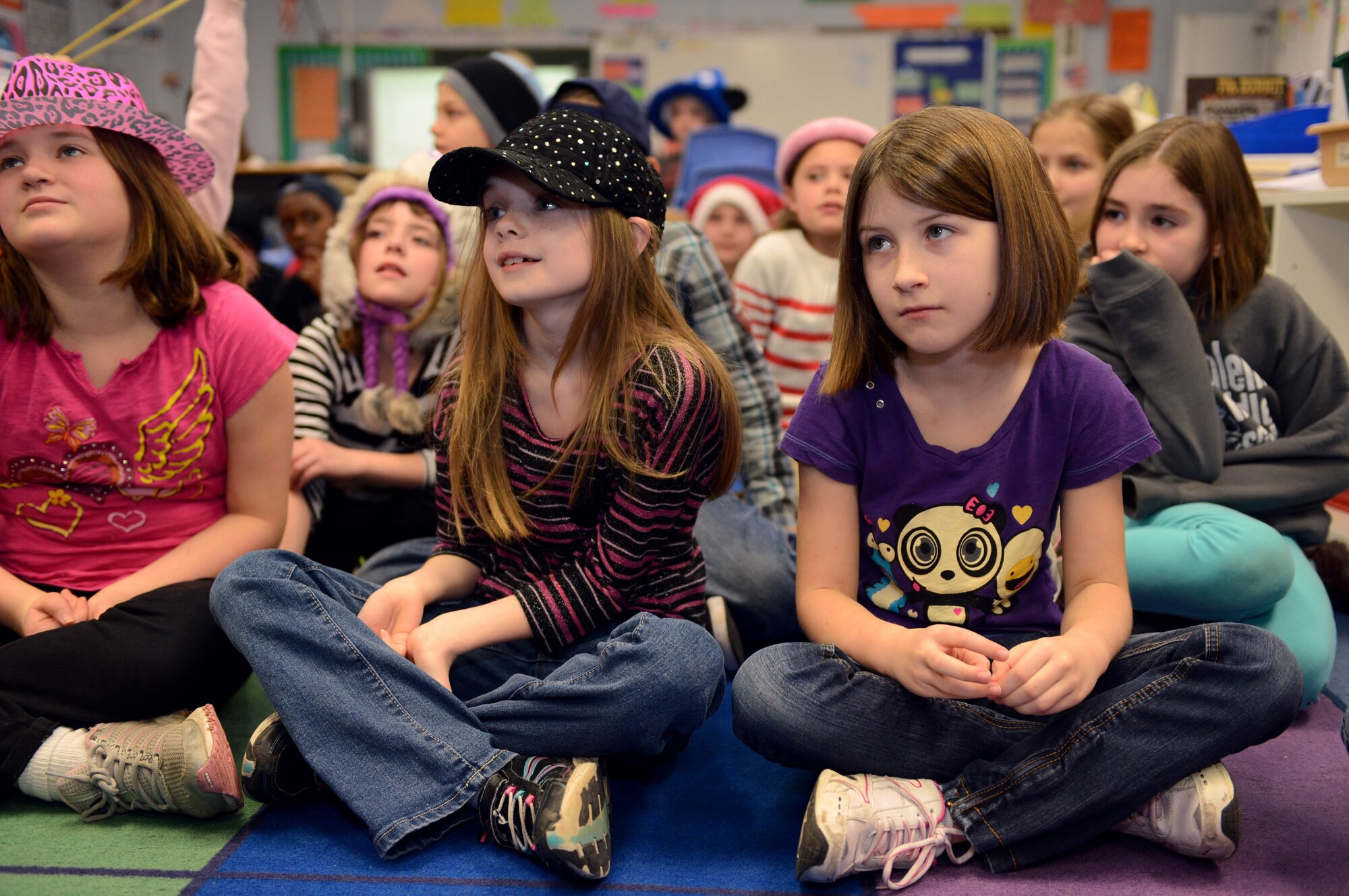 Sierra Lemar, Madison Deslauriers and Gwen Cunningham listen to a volunteer read a Dr. Seuss book during a Read Across America event at Spangdahlem Air Base, Germany, March 3, 2014. The National Education Association represents more than 3 million educators and started National Read Across America in 1998. (U.S. Air Force photo by Airman 1st Class Kyle Gese/Released)