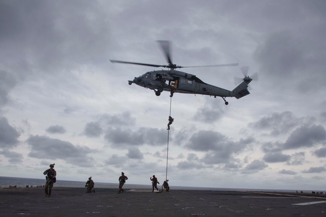 USS BONHOMME RICHARD, At Sea - Marines with the Maritime Raid Force, 31st Marine Expeditionary Unit, rappel from a Navy MH-60S helicopter onto the flight deck of the USS Bonhomme Richard (LHD 6) during fast rope insertion training here, Mar. 2. The Marines utilize rope entry for operations where the helicopter cannot land; such as during a visit, board, search and seizure operation. The 31st MEU is currently conducting amphibious integration training alongside Amphibious Squadron 11 and is deployed for its regularly scheduled Spring Patrol. (Official U.S. Marine Photo by Cpl. Henry Antenor)