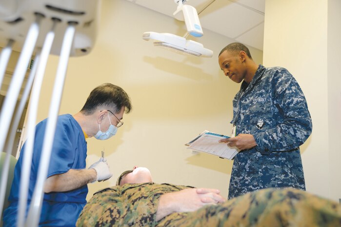 Seaman Aundrea Maddox (right) dental assistant, Naval Dental Clinic, assists Cmdr. Michael Tai, dentist, Naval Dental Clinic, with a Marine’s annual dental cleaning, recently. Maddox is the recipient of the Blue Jacket Award for the Naval Branch Health Clinic Albany’s 4th quarter.