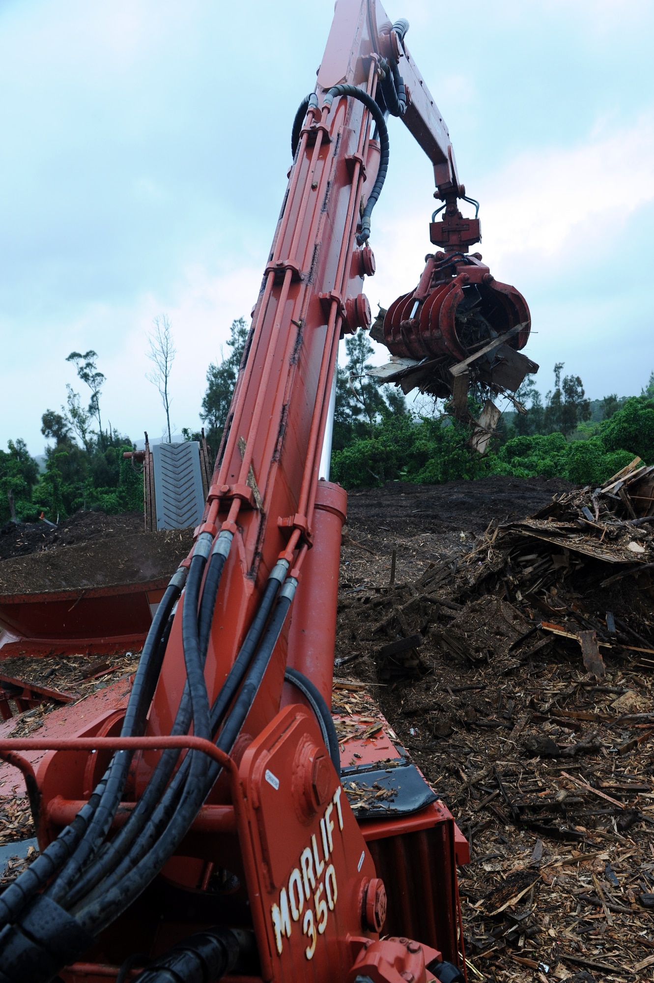 The claw of a Morbark Tub Grinder drops typhoon debris with metal rims into a separate pile of debris on Kadena Air Base, Japan, March 4, 2014. When metal enters the tub grinder, it can severely damage the machine, causing the blades to bind and build pressure in the cavity of the tub. Once too much pressure has built up, blades can shoot through the steel around the tub, causing excessive damage and a major safety issue. (U.S. Air Force photo by Airman 1st Class Hailey R. Staker)