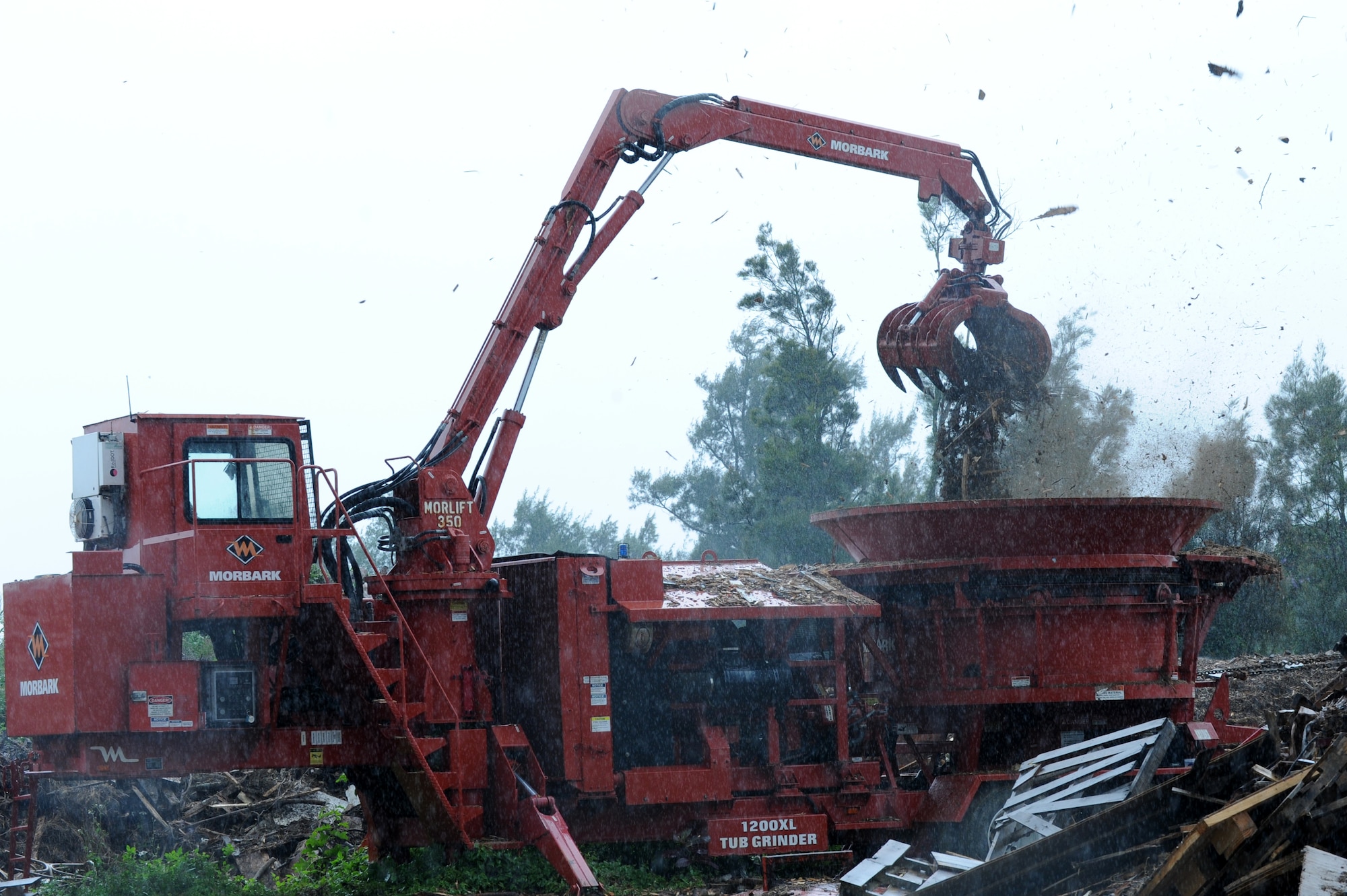Japan Air Self-Defense Force Tech. Sgt. Tatsuya Tsuruta, civil engineer construction worker, drops tree and wood debris left over from typhoon seasons into a Morbark Tub Grinder on Kadena Air Base, Japan, March 4, 2014. This machine grinds any wood debris left over from typhoons or construction to create mulch. (U.S. Air Force photo by Airman 1st Class Hailey R. Staker)
