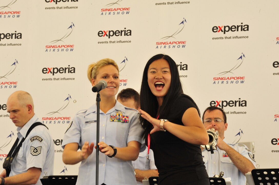CHANGI, Singapore—Staff Sergeant Courtney Clifford, Band of the Pacific-Hawaii, sings with Seven Zhan, Chief Executive of Chatal S.A.S of China, at the Singapore Air Show, Feb. 12, 2014. The group played 9 shows to over 100K audience members throughout their tour. The Band of the Pacific-Hawaii went to Singapore in support of the air show, the U.S. Embassy, and to improve international relations. (US Air Force Photo/ SrA Andy Detra/released)