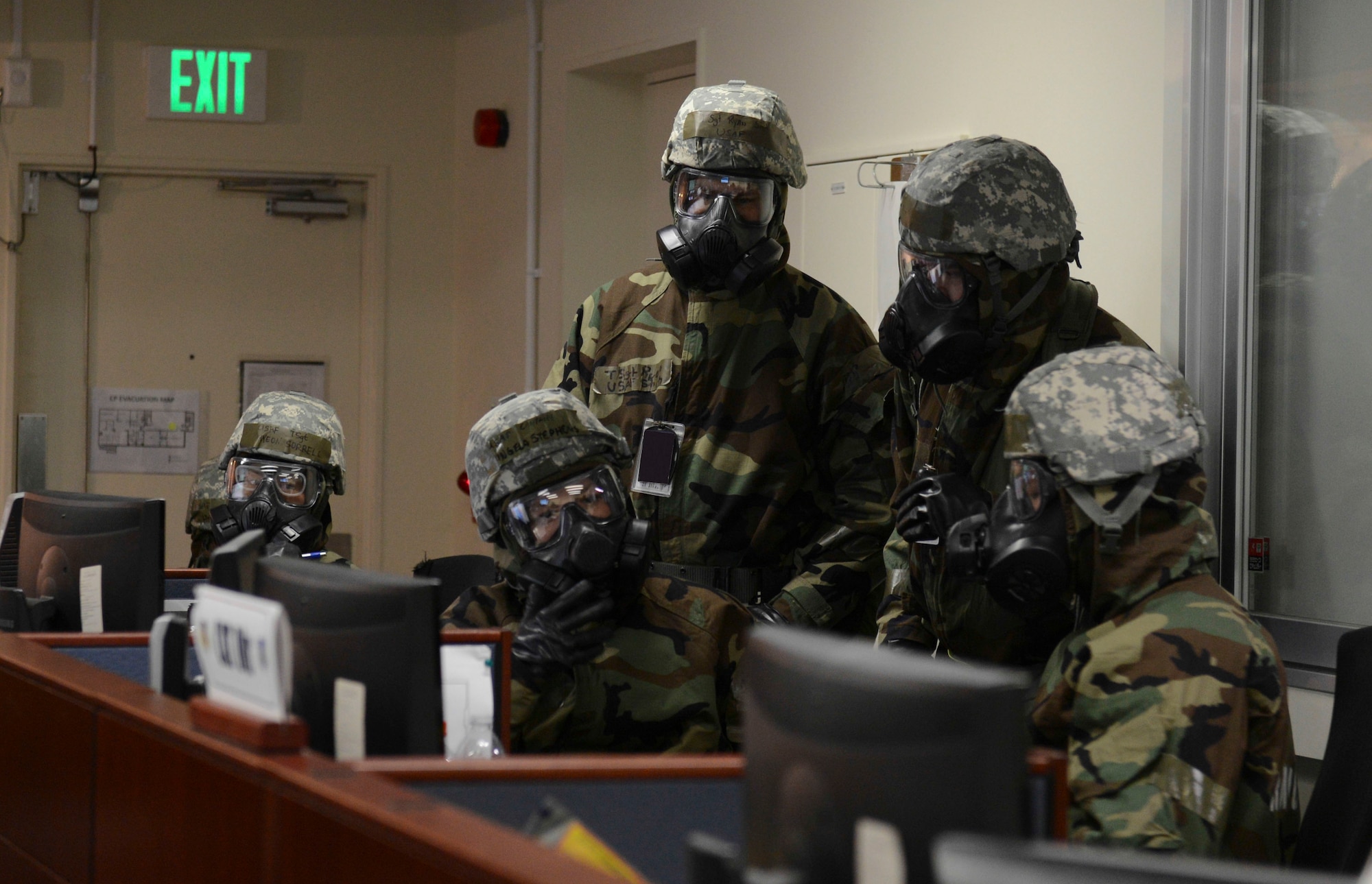 Airmen wearing Mission Oriented Protective Posture gear discuss the current situation of the exercise at Yokota Air Base, Japan, March 6, 2014. The Commander’s Action Team, consisting of representatives from each unit around the base, delivers fast and accurate information between the commander and their respectable units. (U.S. Air Force photo by Airman 1st Class Meagan Schutter/Released)
