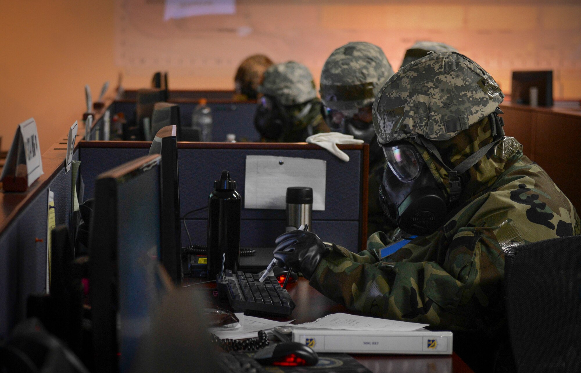An Airman wearing Mission Oriented Protective Posture gear types on a computer using two pens during the Samurai Readiness Inspection at Yokota Air Base, Japan, March 6, 2014. The SRI tested Yokota’s Airmen to ensure they were ready to respond to any type of contingency that may happen in the real world. (U.S. Air Force photo by Airman 1st Class Meagan Schutter/Released)