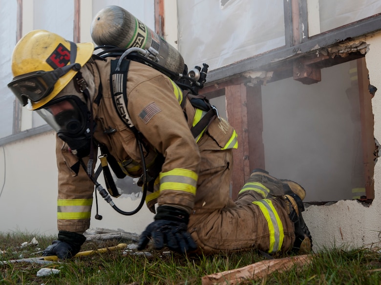 VANDENBERG AIR FORCE BASE, Calif. – Eric Klinedinst, 30th Civil Engineering Squadron firefighter, crawls out of a simulated burning building after breaching though a wall here Feb. 14. Military and civilian firefighters along with the Hot Shots got an opportunity to perform different skills on the old education building set to be demolished within the next few months. U.S. Air Force photo/Airman 1st Class Yvonne Morales) ) 