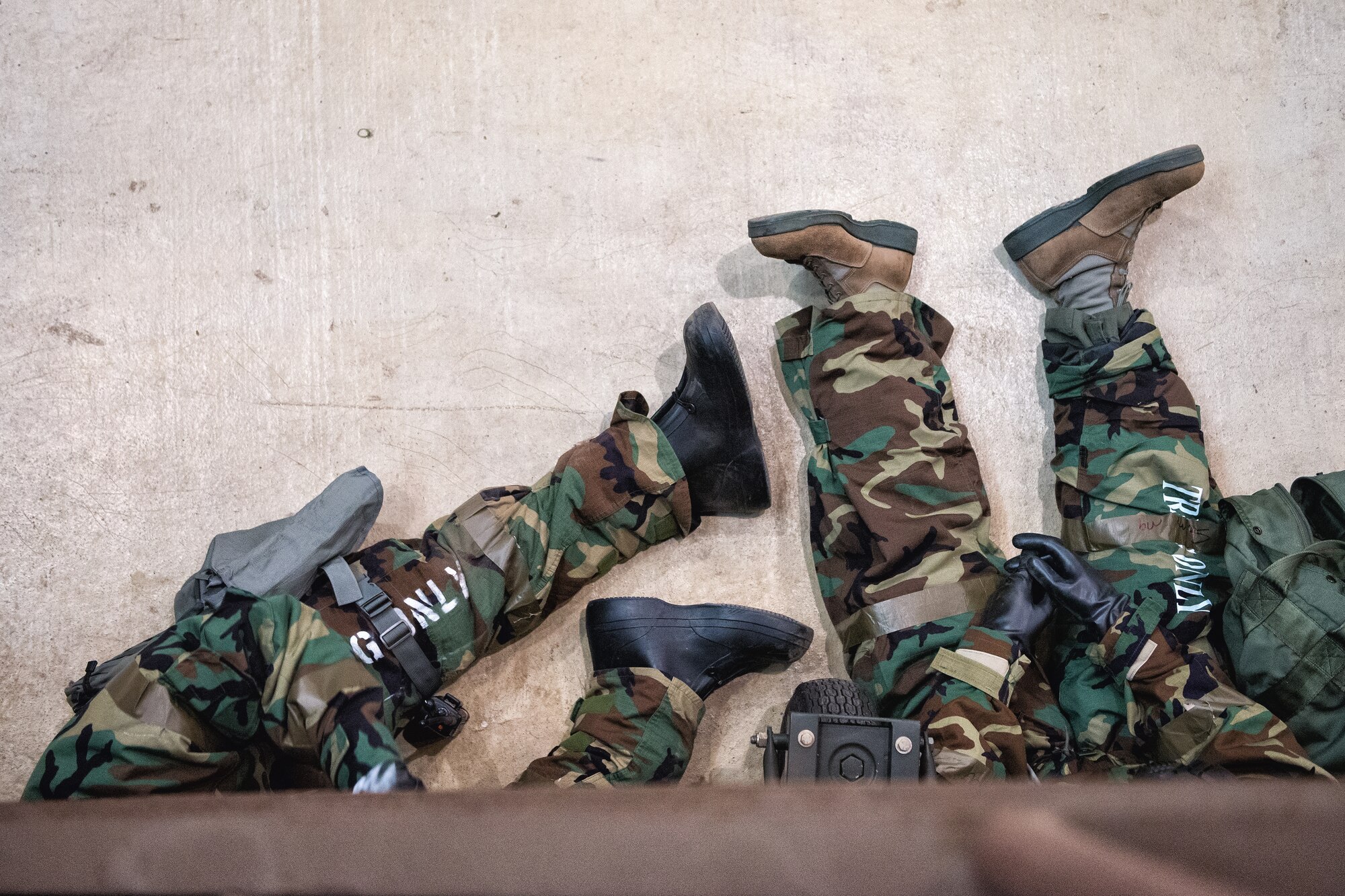 Airmen from the 374th Aircraft Maintenance Squadron take cover while donning their chemical protection equipment during a Samurai Readiness Inspection at Yokota Air Base, Japan, March 5, 2014. The Samurai Readiness Inspection tests Yokota’s ability to carry out its mission as the airlift hub in the Pacific during contingency operations. (U.S. Air Force photo by Staff Sgt. Dustin Payne/Released)