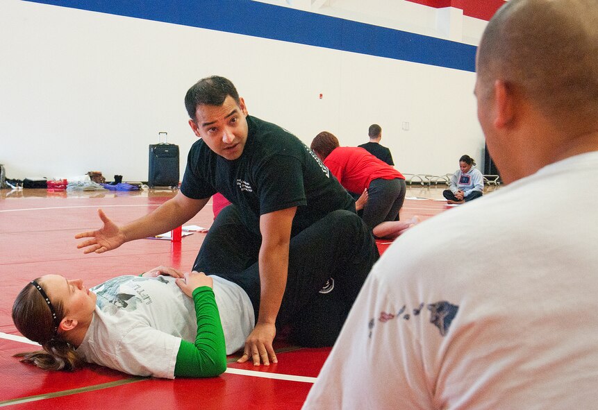 Tech. Sgt. Eric Barrera, 90th Maintenance Operations Squadron assistant NCO-in charge of Electronics Lab, with the help of Senior Airman Alicia Johnson, 90th Security Forces Squadron, echoes the training instruction given to him by Gracie Jiu Jitsu Academy instructors to Master Sgt. Michael Canne, 20th Air Force Security Forces directorate, Plans and Programs superintendent, during the Gracie Defense Systems training course in the Freedom Hall Fitness Center Feb. 28, 2014. The training lasted through the work week and the training aimed at giving the participants the ability to spread the techniques to their fellow Airmen who were unable to attend. (U.S. Air Force photo by Airman 1st Class Jason Wiese)