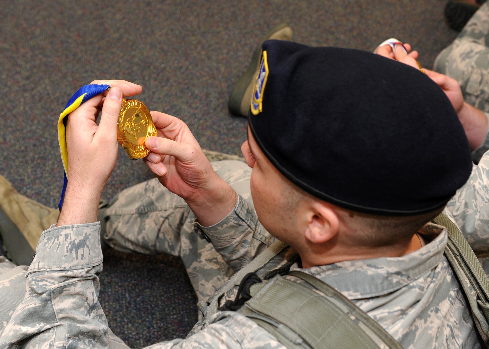Airman 1st Class Christopher Petersen, 341st Missile Security Forces Squadron member, looks at a medal that Anne Battelle, former U.S. Olympic mogul skier, won during the Goodwill Games in 2000. Battelle and Erin Simmons-Nemec, former U.S. Olympic snowboarder, visited with Airmen across Malmstrom Air Force Base to share challenges they faced while chasing their dream of competing in the Olympics. (U.S. Air Force photo/Senior Airman Katrina Heikkinen)