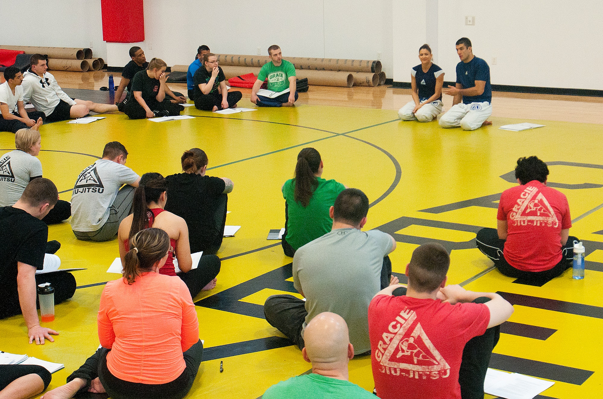 A class composed of Airmen and their spouses listens to Gracie Defense Systems instructors in the Freedom Hall Fitness Center Feb. 28, 2014, as they explain ways to avoid and defend against assaults. (U.S. Air Force photo by Airman 1st Class Jason Wiese)