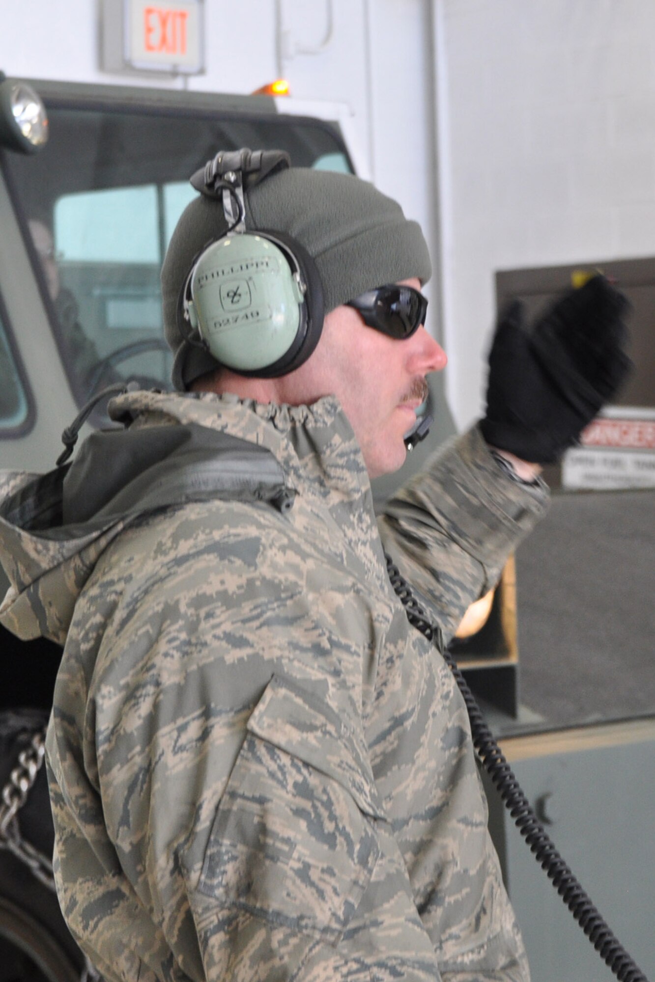 YOUNGSTOWN AIR RESERVE STATION, Ohio – Air Force Reserve Master Sgt. Sam Phillippi, crew chief of 910th Airlift Wing Tail 3021, a C-130 Hercules cargo aircraft, motions to a tow motor driver in a maintenance hangar during flight preparations here, March 3, 2014. The tow motor is pushing Tail 3021 out of the hangar and will maneuver the aircraft onto the air station flightline as it is prepared to depart here for the final time. The C-130 is to being transferred to Little Rock Air Force Base, Ark. as part of recent Air Force structure changes. The departure of 3021 from YARS leaves the 910th with eight primary C-130 aircraft and one back up aircraft assigned to the unit. U.S. Air Force photo by Master Sgt. Bob Barko Jr.