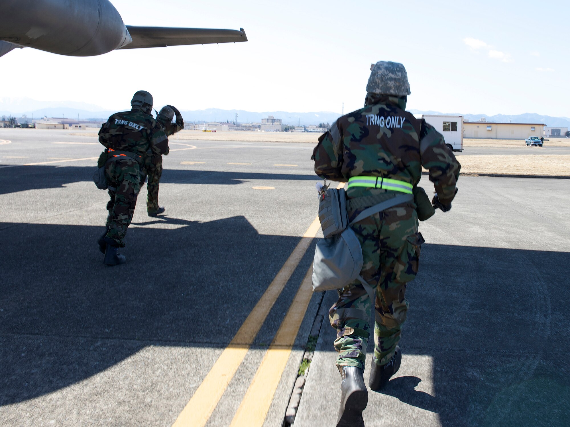 Airmen run to take cover during a simulated attack while wearing their mission-oriented protective posture gear during Samurai Readiness Inspection at Yokota Air Base, Japan, March 6, 2014. Yokota Airmen were challenged with numerous scenarios such as a chemical warfare attack. (U.S. Air Force photo by Airman 1st Class David Danford / released)