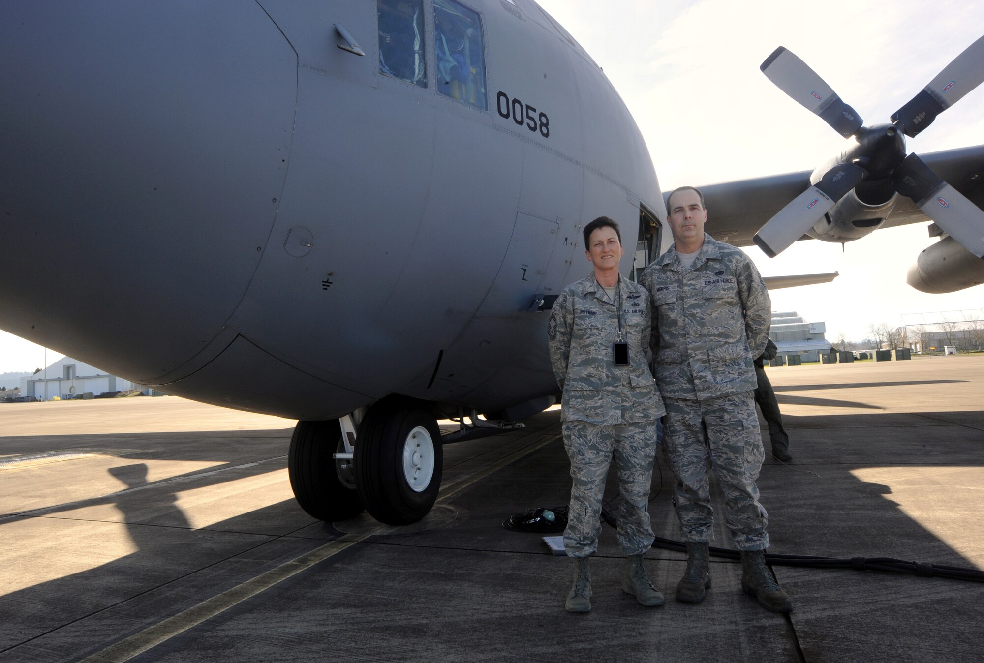 Oregon Air National Guard Logistical Readiness Squadron members Senior Master Sgt. Pam Pittman and Tech. Sgt. Michael Morris, 142nd Fighter Wing, pause for a photograph next to a C-130 Hercules, at the Portland Air National Guard Base, Ore., Feb. 27, 2014. (U.S. Air National Guard photo by Tech. Sgt. John Hughel/Released)