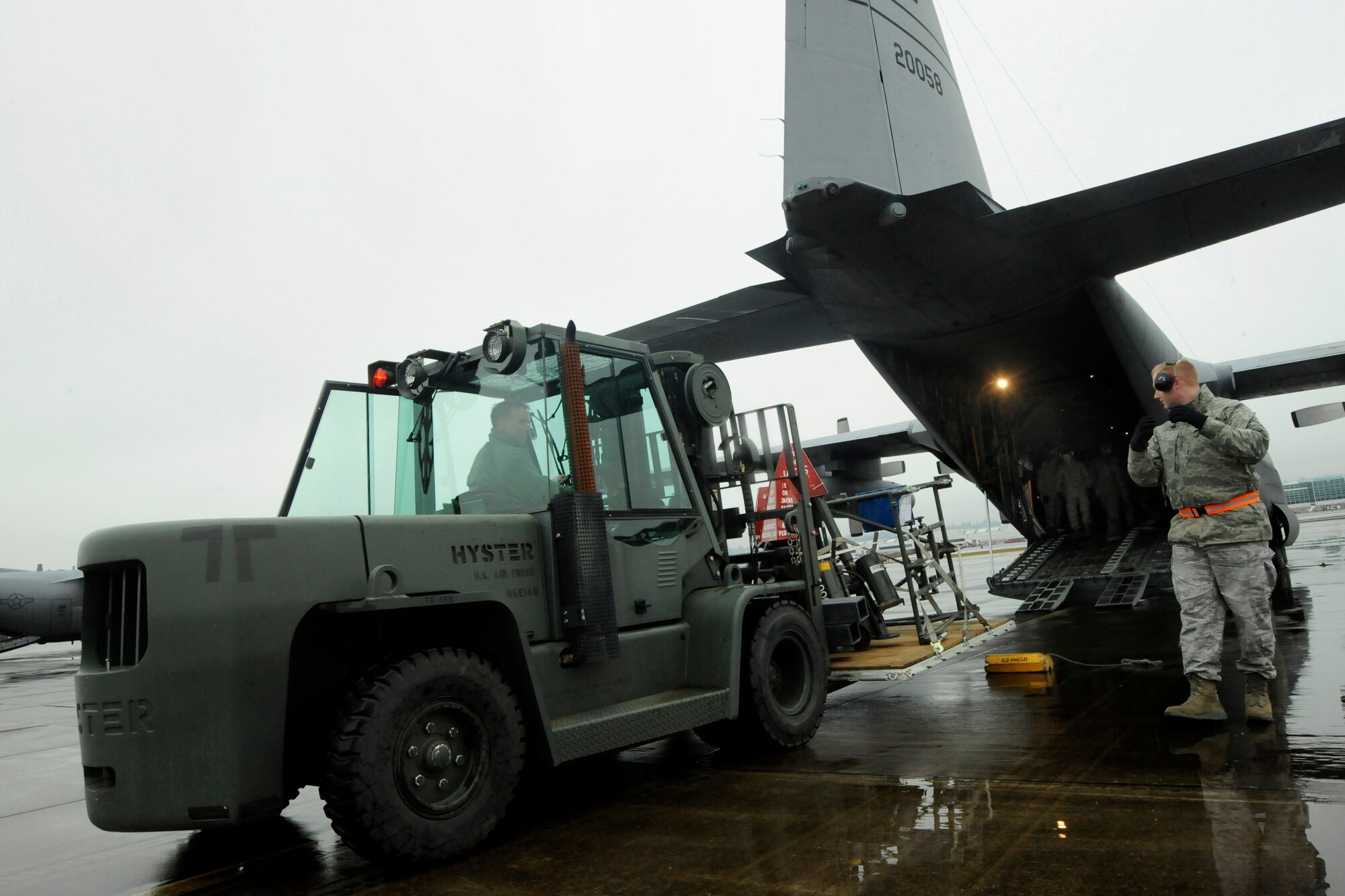 Oregon Air National Guard members Tech. Sgt. Sam Riggs spots Tech. Sgt. Michael Jones as he moves a fork lift into place as they load a C-130 Hercules, at the Portland Air National Guard Base, Ore., Feb. 27, 2014. Jones and Riggs, 142nd Fighter Wing Logistics Readiness Squadron members, are packing equipment that will be used in the Red Flag exercise at Nellis Air Force Base, Nev. (U.S. Air National Guard photo by Tech. Sgt. John Hughel/Released)