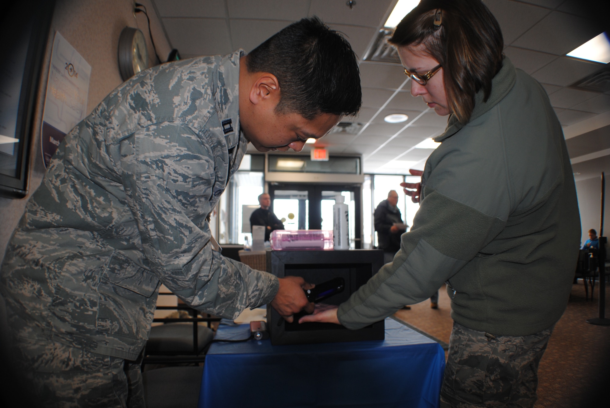 Capt. Chris Ordonez, 319th Medical Group infection preventionist, checks Senior Airman Annabel Pack’s hand for dirt using a black light during a Glo Germ challenge March 3, 2014, at the pharmacy on Grand Forks Air Force Base, N.D. Pack, a 319th Air Base Wing Command Post emergency action controller, participated in the challenge as part of a series of activities put on by the 319th MDG in observance of National Patient Safety Week. (U.S. Air Force photo/Staff Sgt. Luis Loza Gutierrez) 
